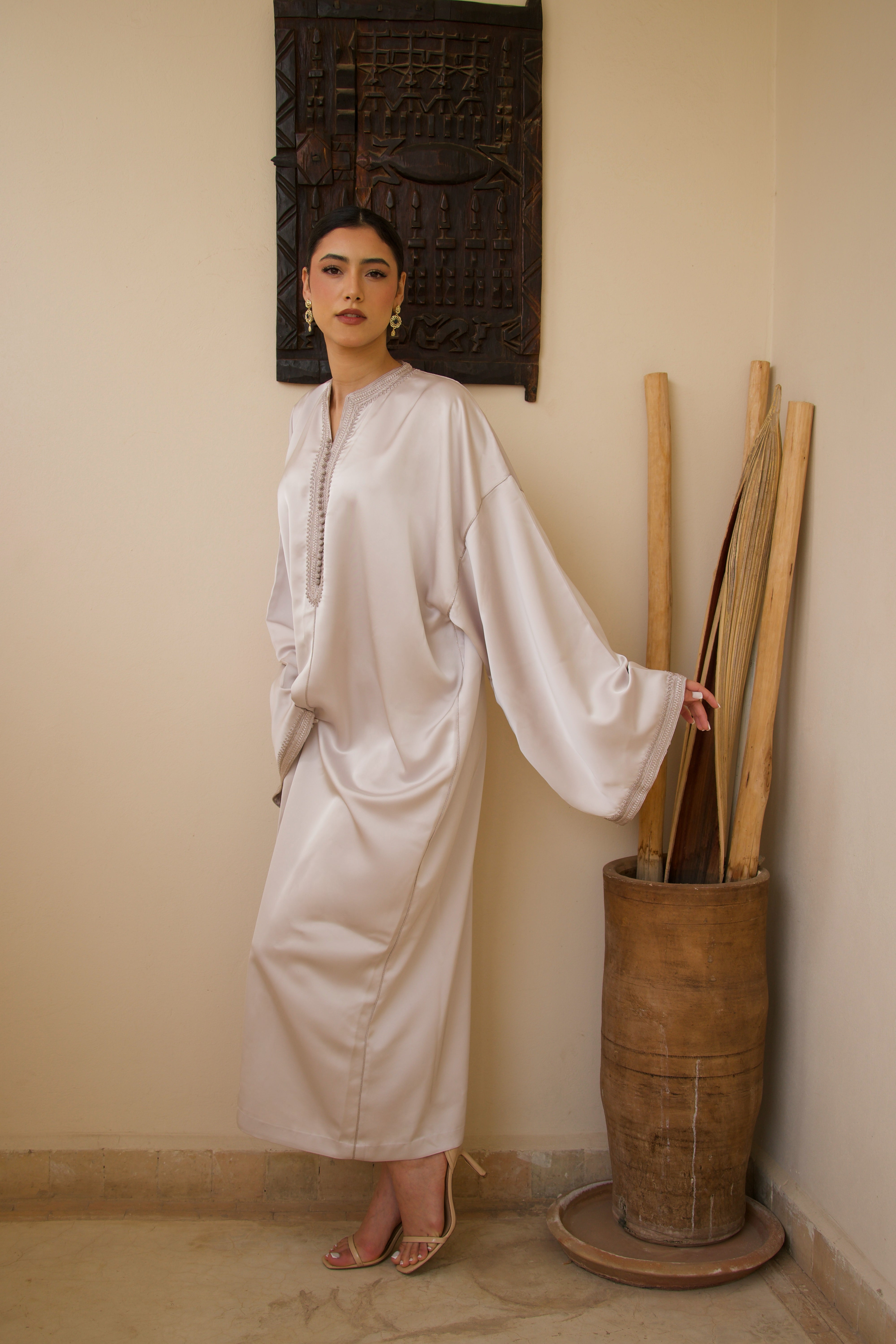 Jellaba blanche en satin duchesse portée en mouvement, tissu fluide et structuré.