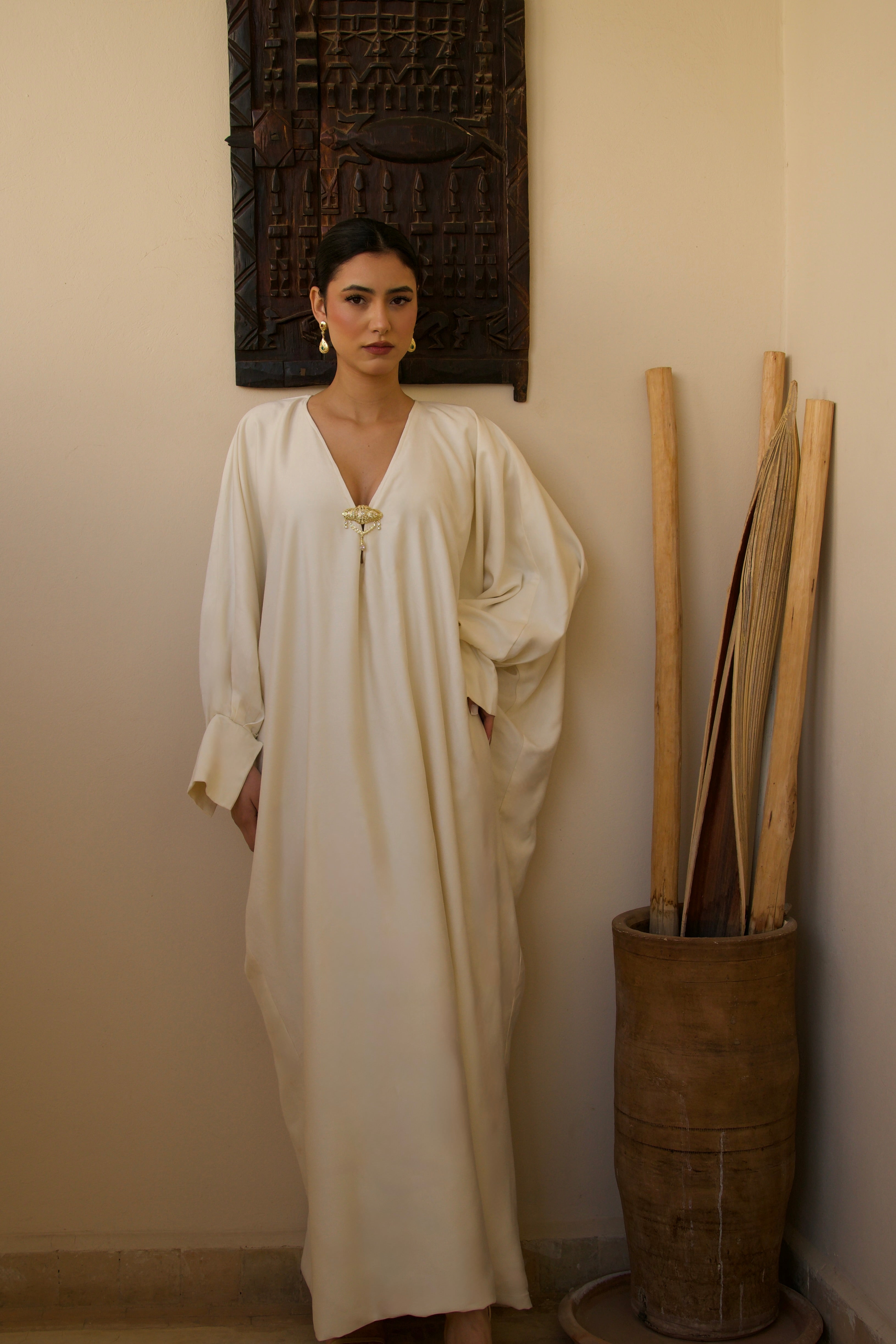 Robe longue blanche en soie mlifa ornée d’une broche marocaine, vue de face.