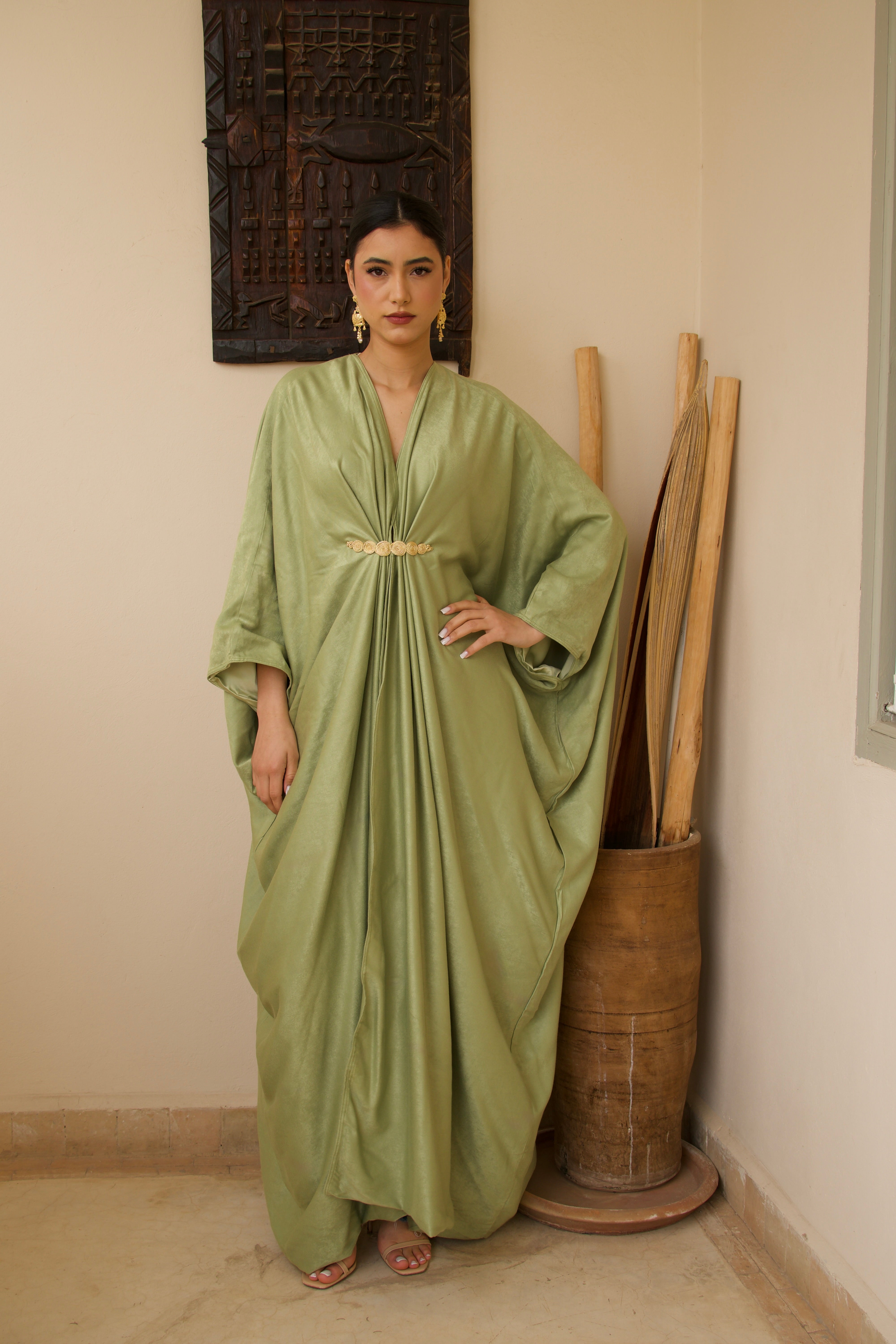 Robe longue verte en soie mlifa avec drapé élégant et broche marocaine, vue de face.