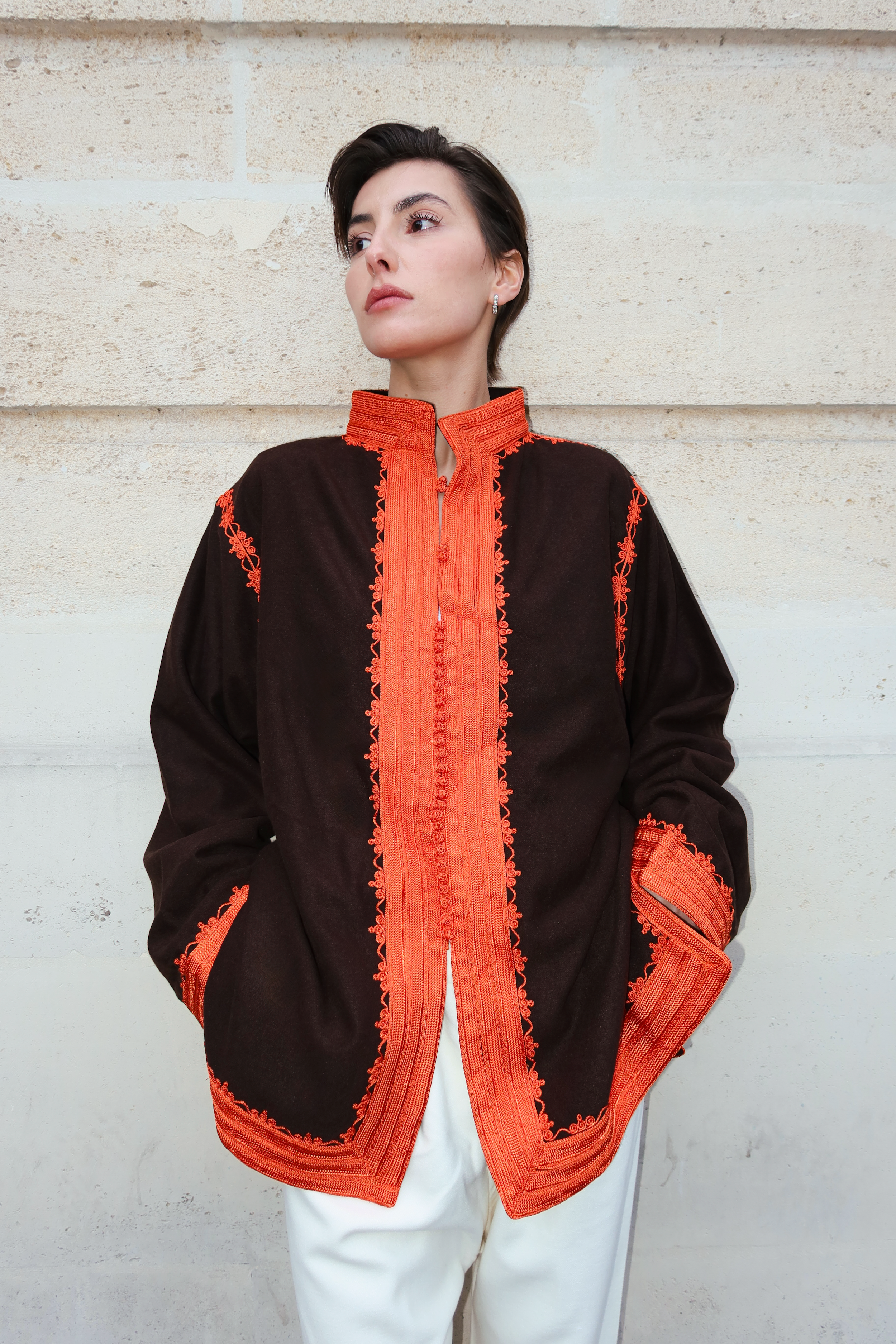 Veste en cachemire marron en mouvement révélant la douceur du tissu et des broderies orange raffinées