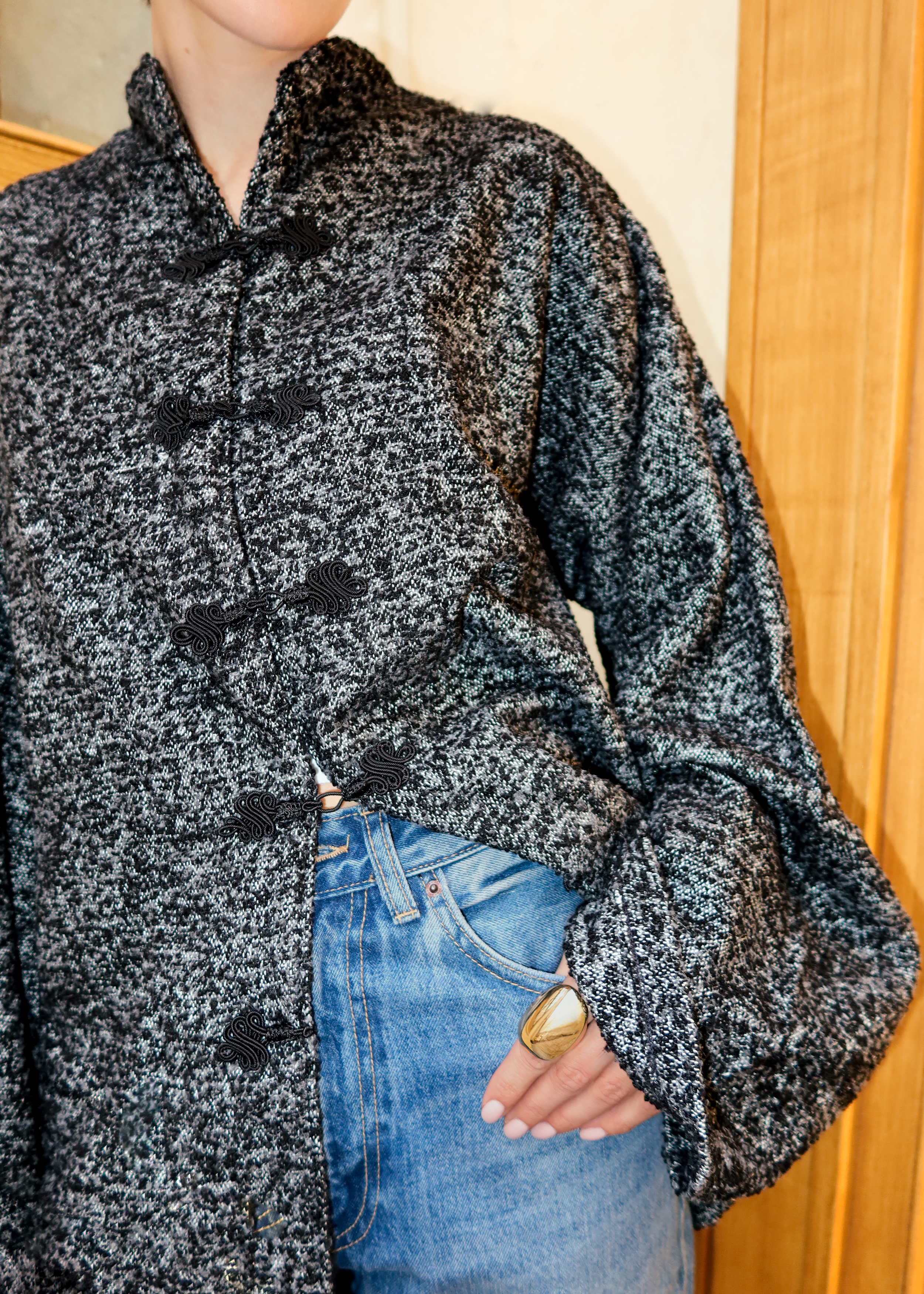 Veste en laine bouclée noire en mouvement révélant une coupe moderne et des boutons marocains élégants