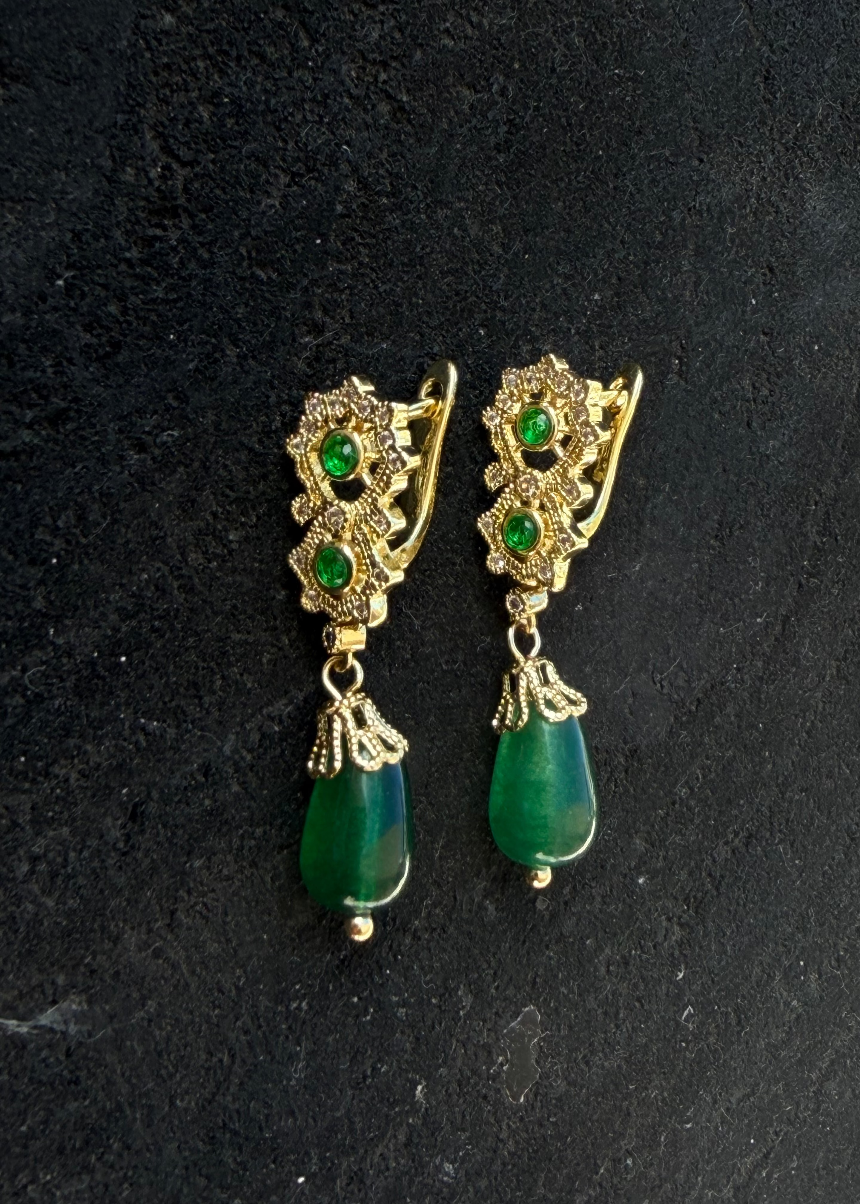 Gold earrings with green teardrop pendants, openwork frames, and clear stones