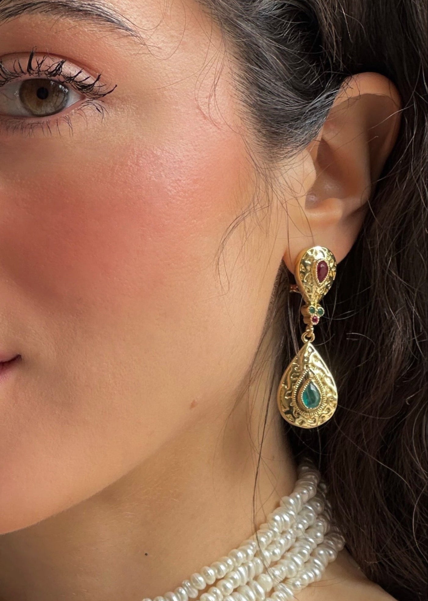 Rose- and green-accented teardrop earrings being worn