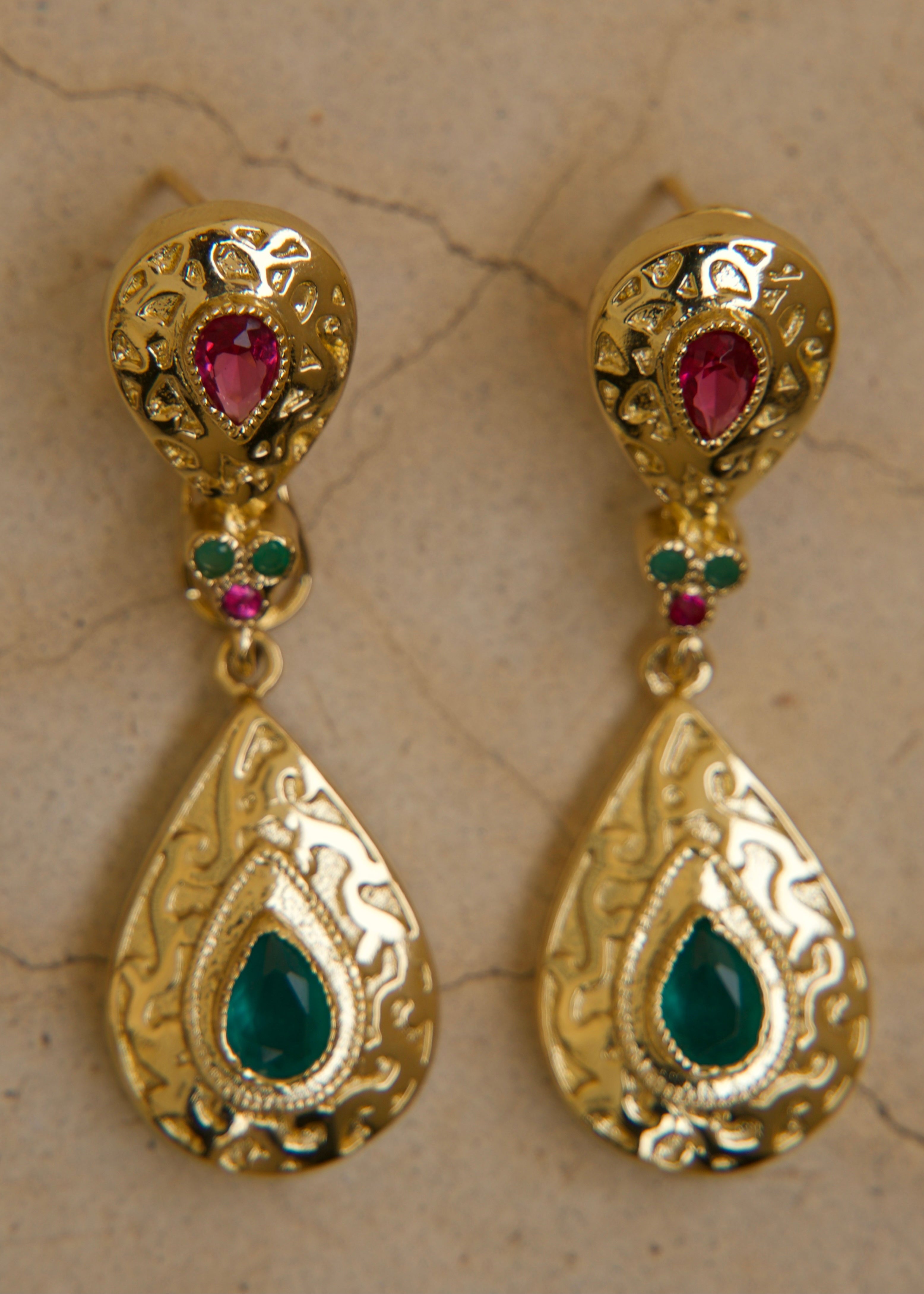 Gold earrings with large engraved teardrops, featuring pink and green stones, an oriental statement piece
