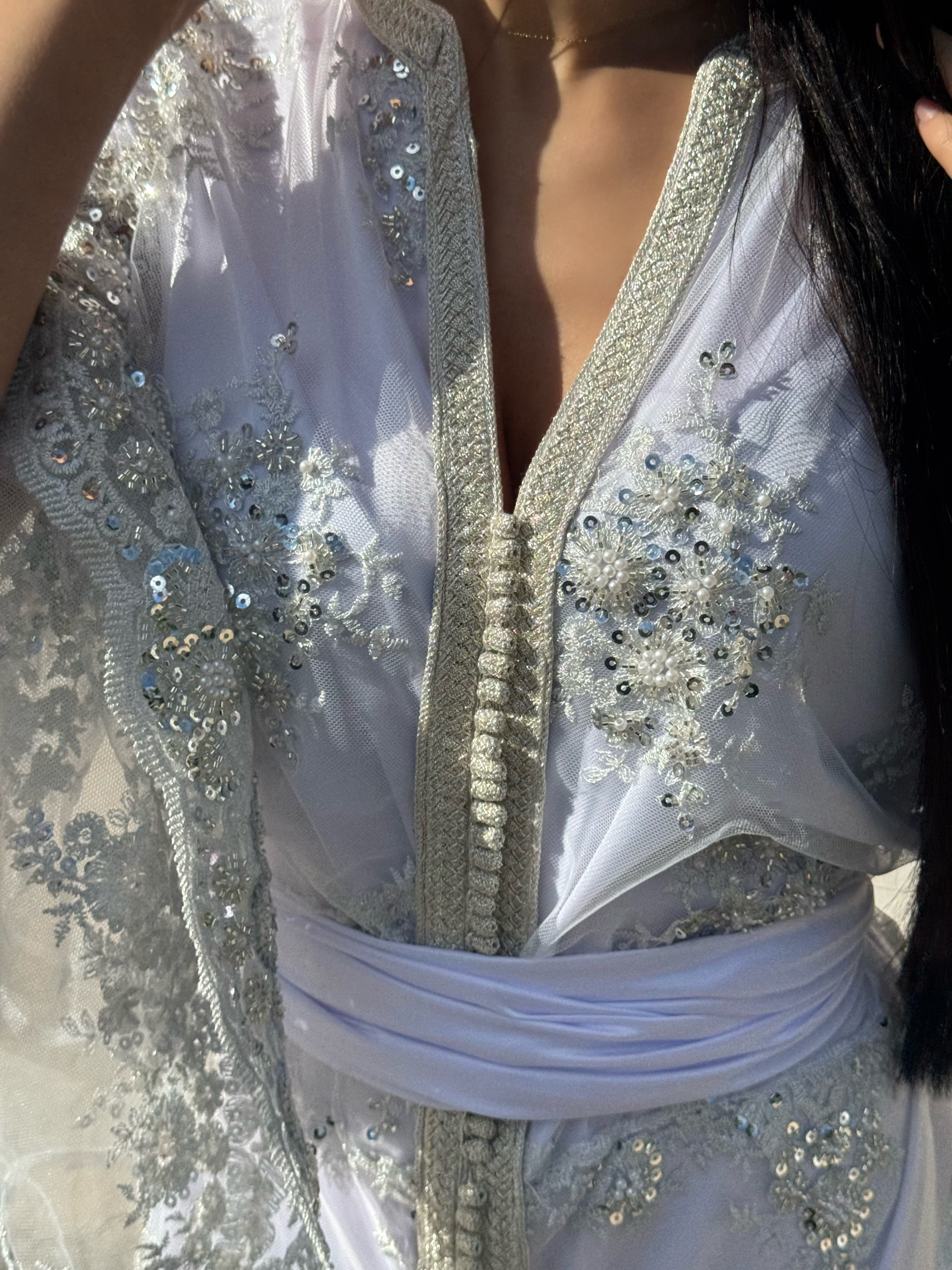 Close-up of the embroidered bodice on a white Kaftan adorned with beads

