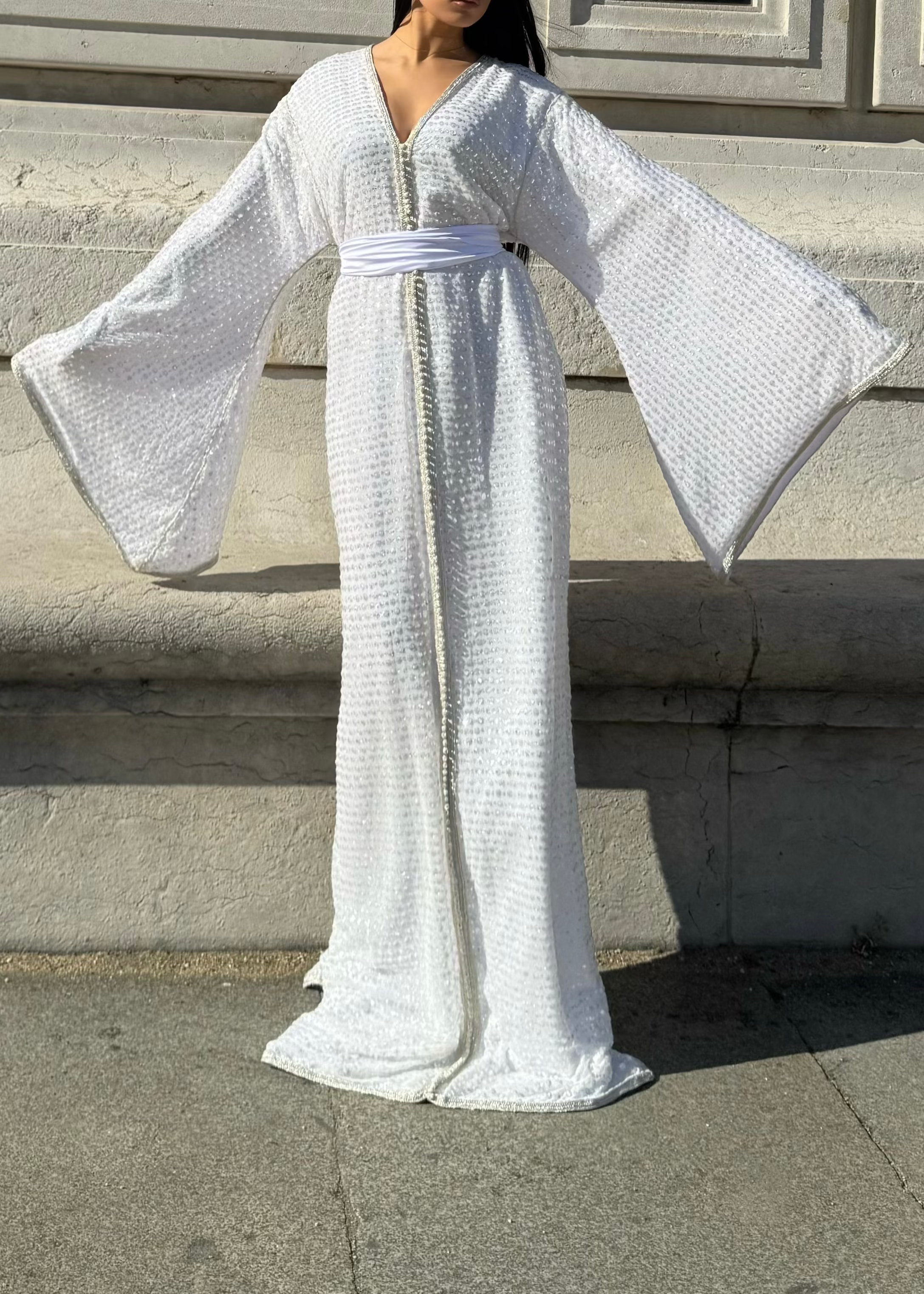 A radiant white Kaftan with wide sleeves and a flowing, floor-length silhouette
