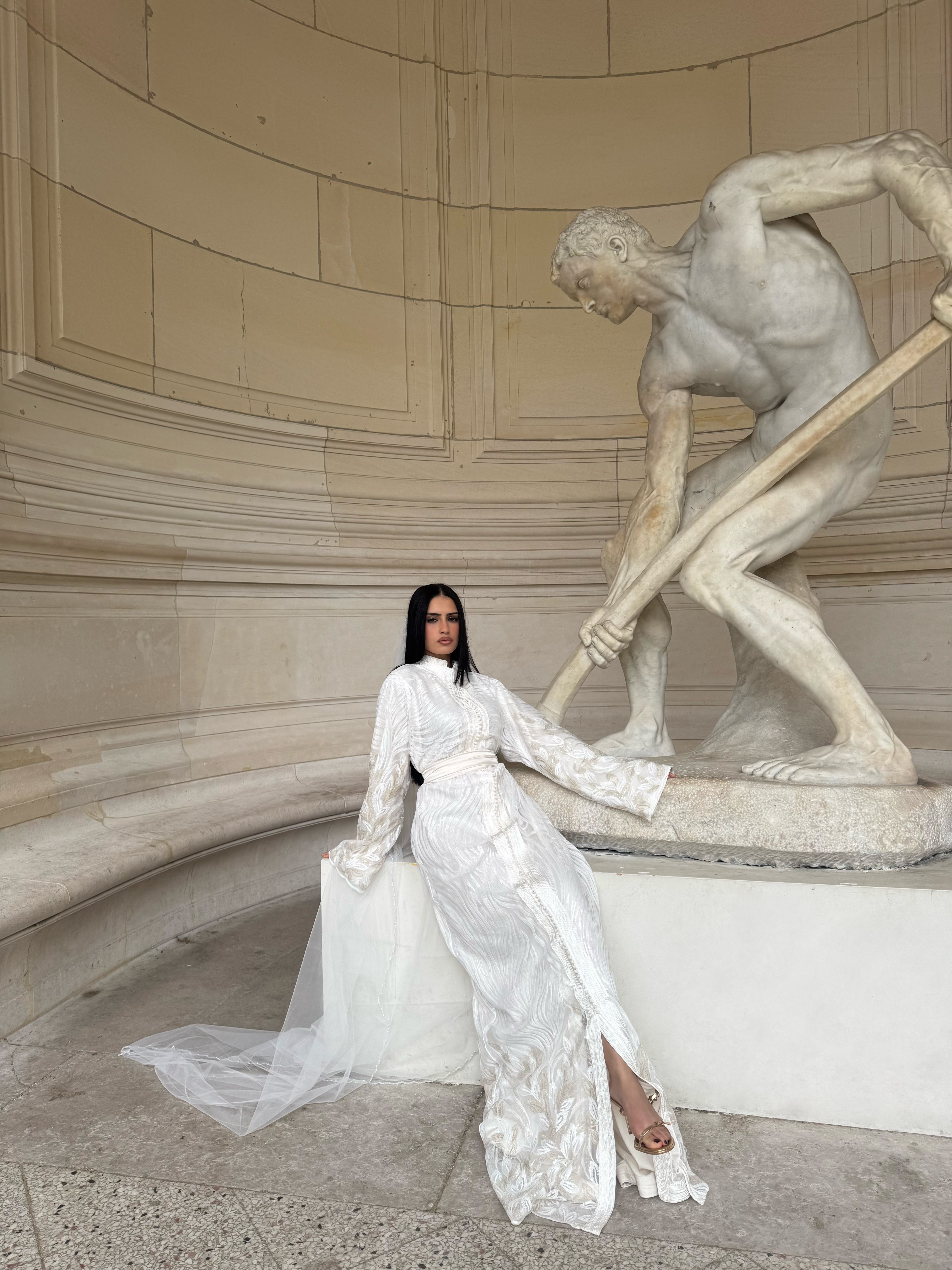 Kaftan textured white Kaftan worn while seated in a sculptural setting
