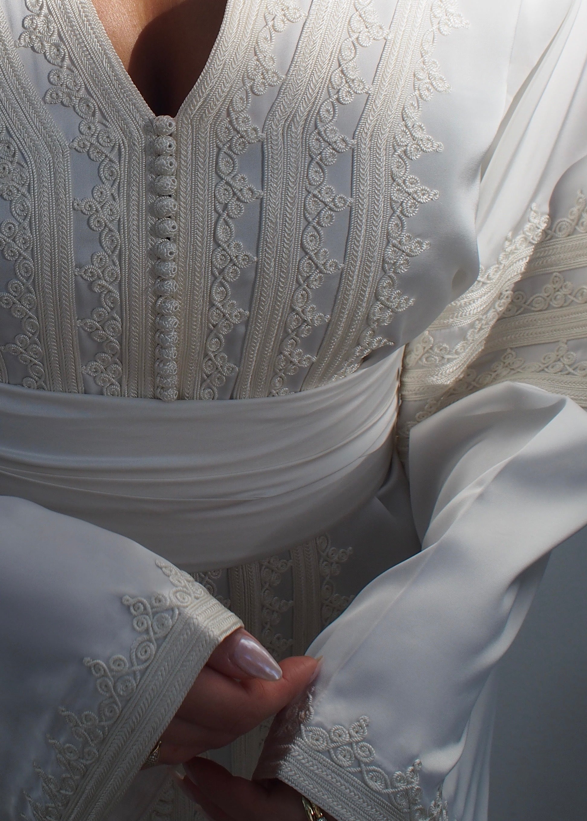 Zoom sur le caftan en drap de soie blanc.