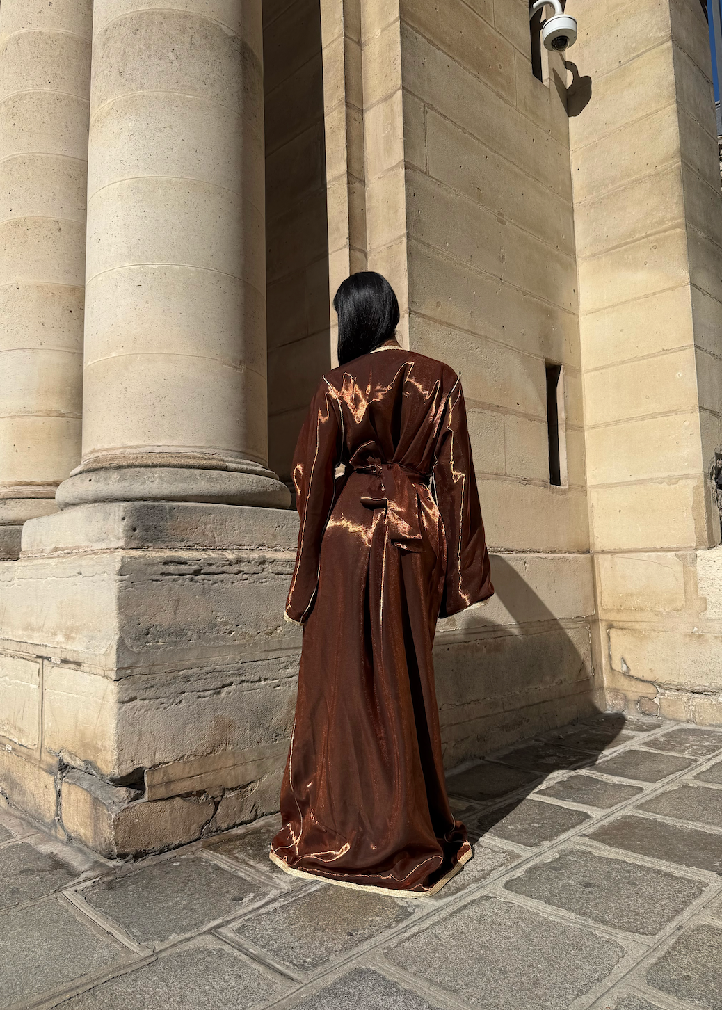 Vue de dos du caftan avec ceinture corset et tombé fluide en satin métallisé.