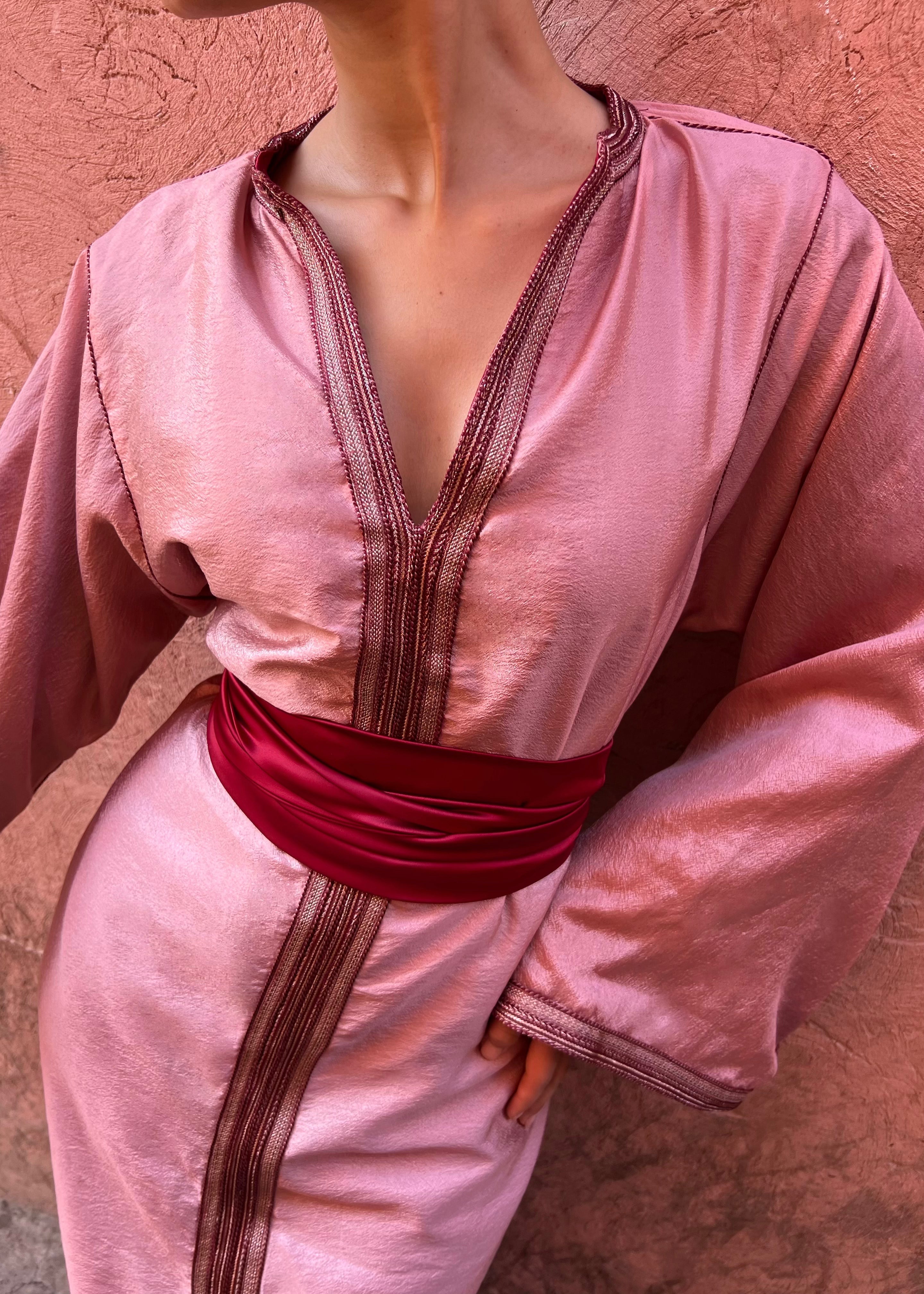 Détail du drapé en satin rose du caftan moderne, texture soyeuse et finitions couture élégantes