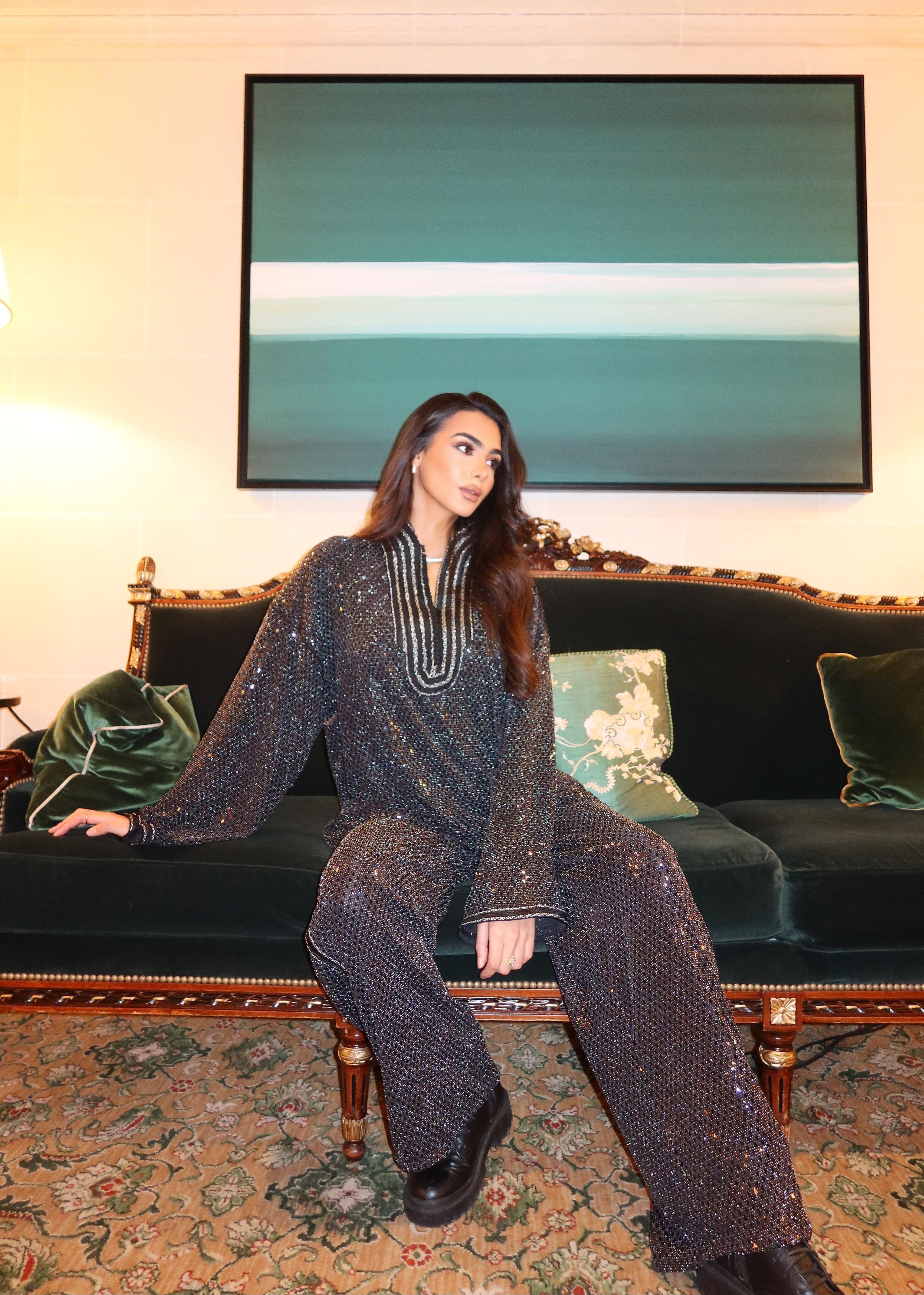 Ensemble noir scintillant en jacquard avec sfifa en mouvement, effet lumineux et allure fluide et chic. Photo assise de plein pied
