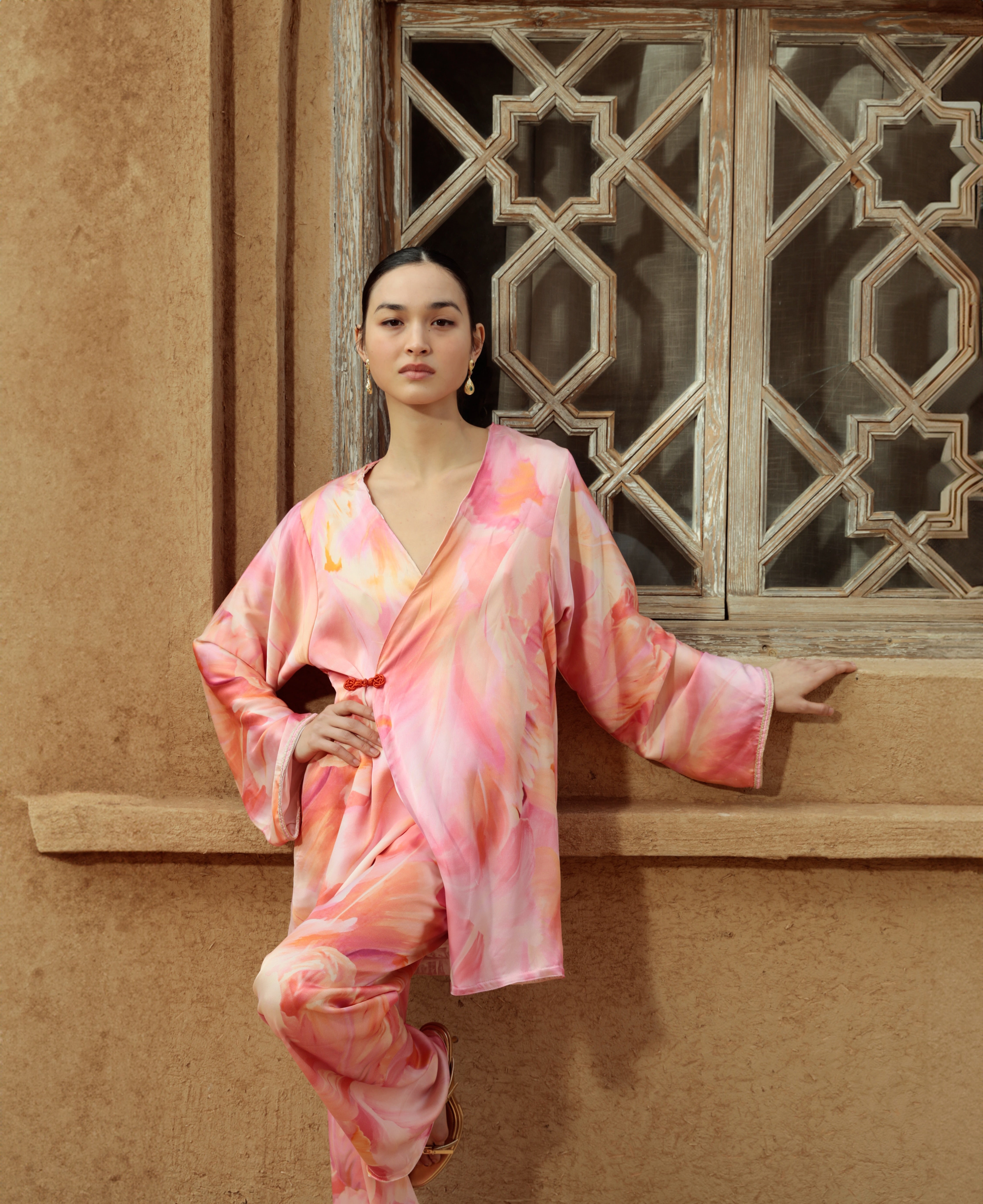 Ensemble fluide rose et orange porté, avec tunique croisée et pantalon imprimé
