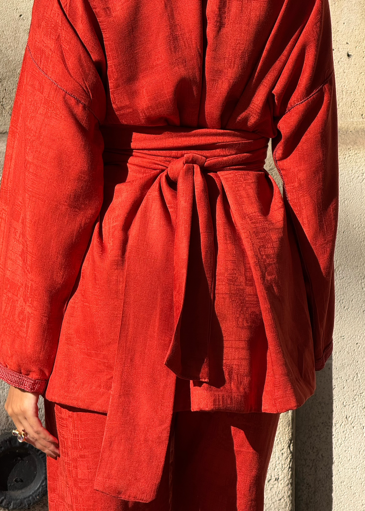 Zoom sur la ceinture du kimono rouge en soie Mlifa, décorée de sfifa artisanale et boutons bordeaux