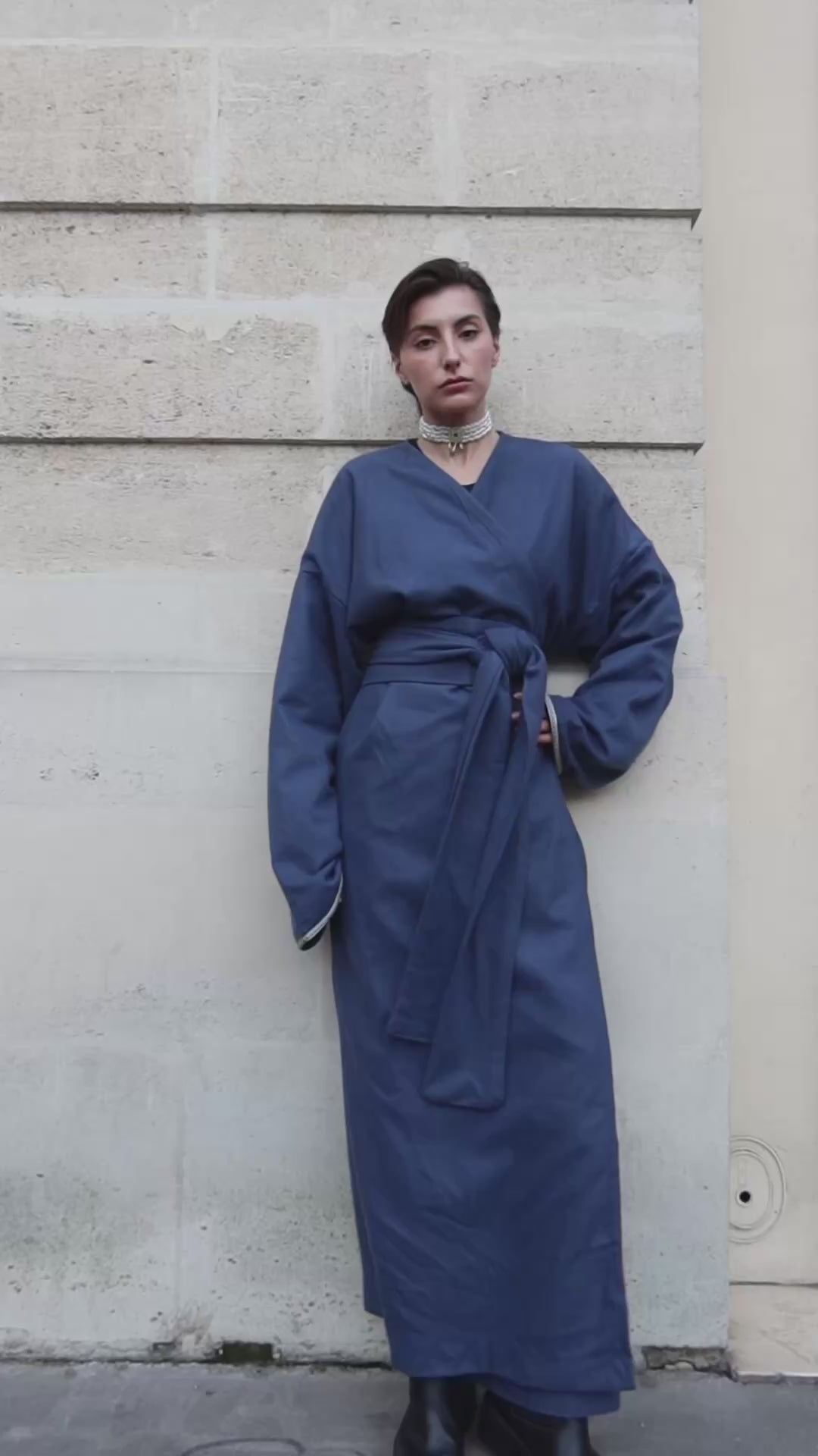 Vidéo portée d’un gilet long en cachemire bleu avec des détails de sfifas sur les manches. 