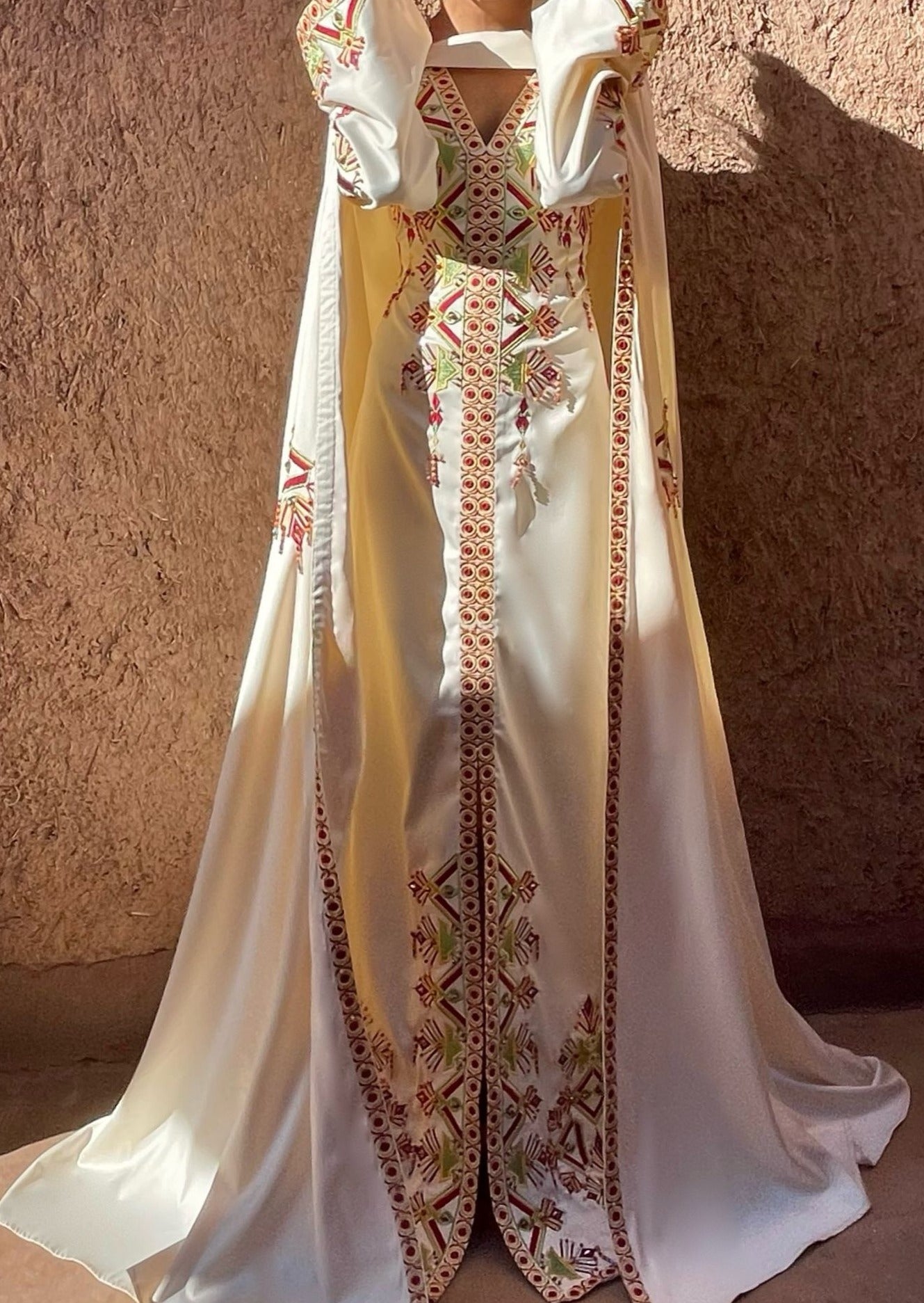 فستان الزفاف القبائلي مع البرنوس الذي يظهر من الأمام، مما يبرز ثراء التطريز التقليدي وفخامة الطرحة.