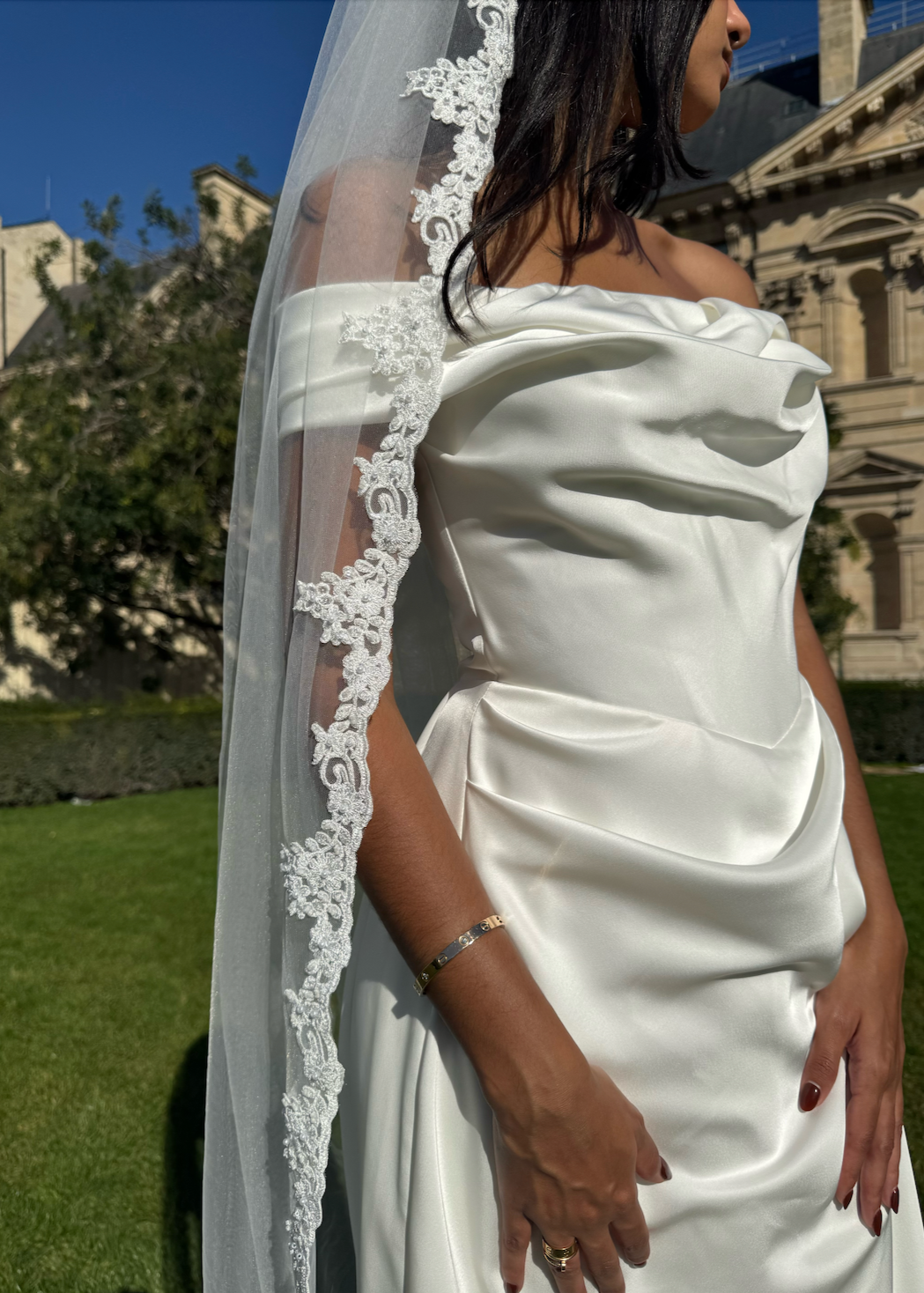 Gros plan sur la dentelle florale en bordure du voile de mariée, finement travaillée.

