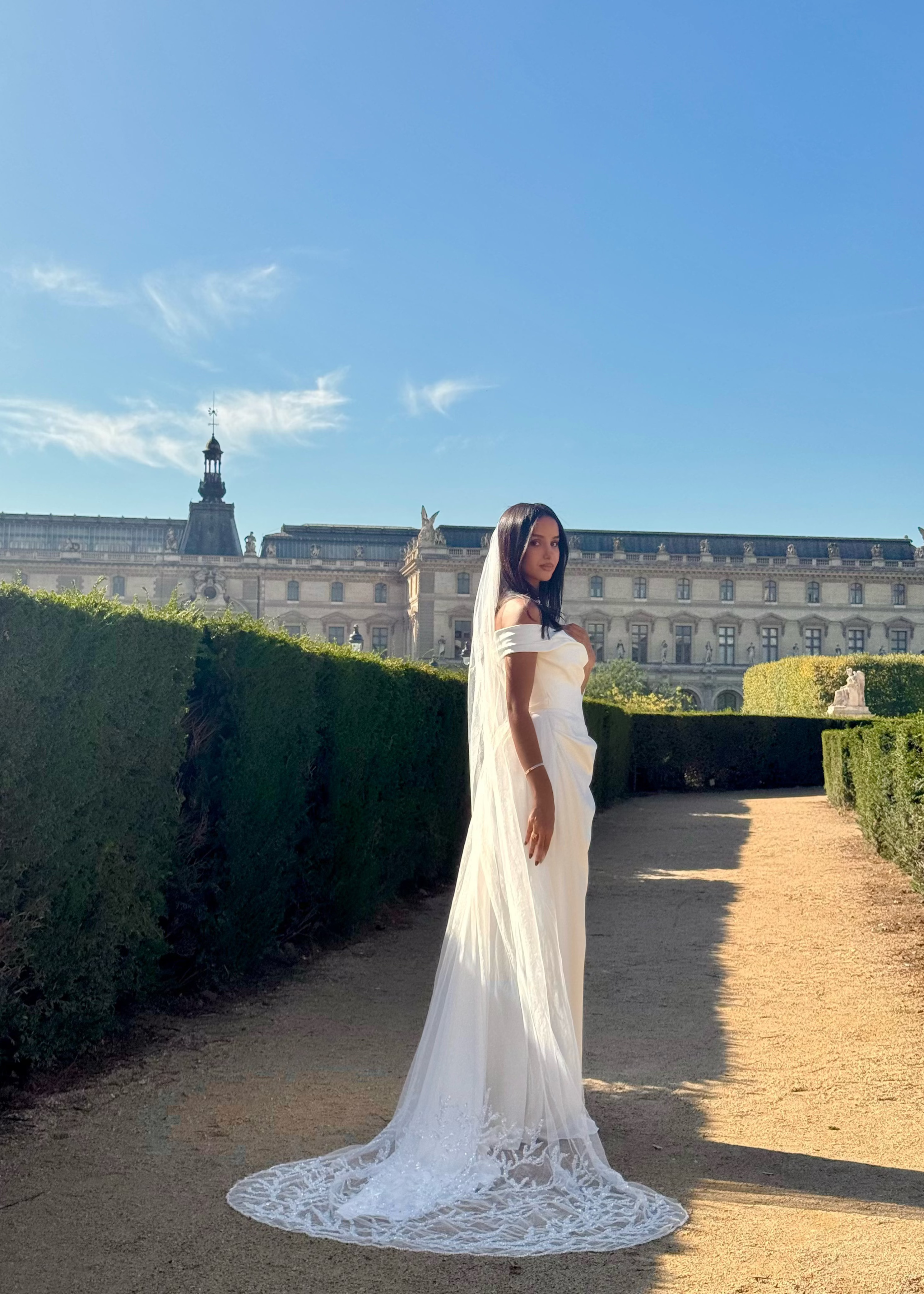 Vue trois-quarts arrière d'une mariée avec voile brodé de motifs feuillus et perles délicates
