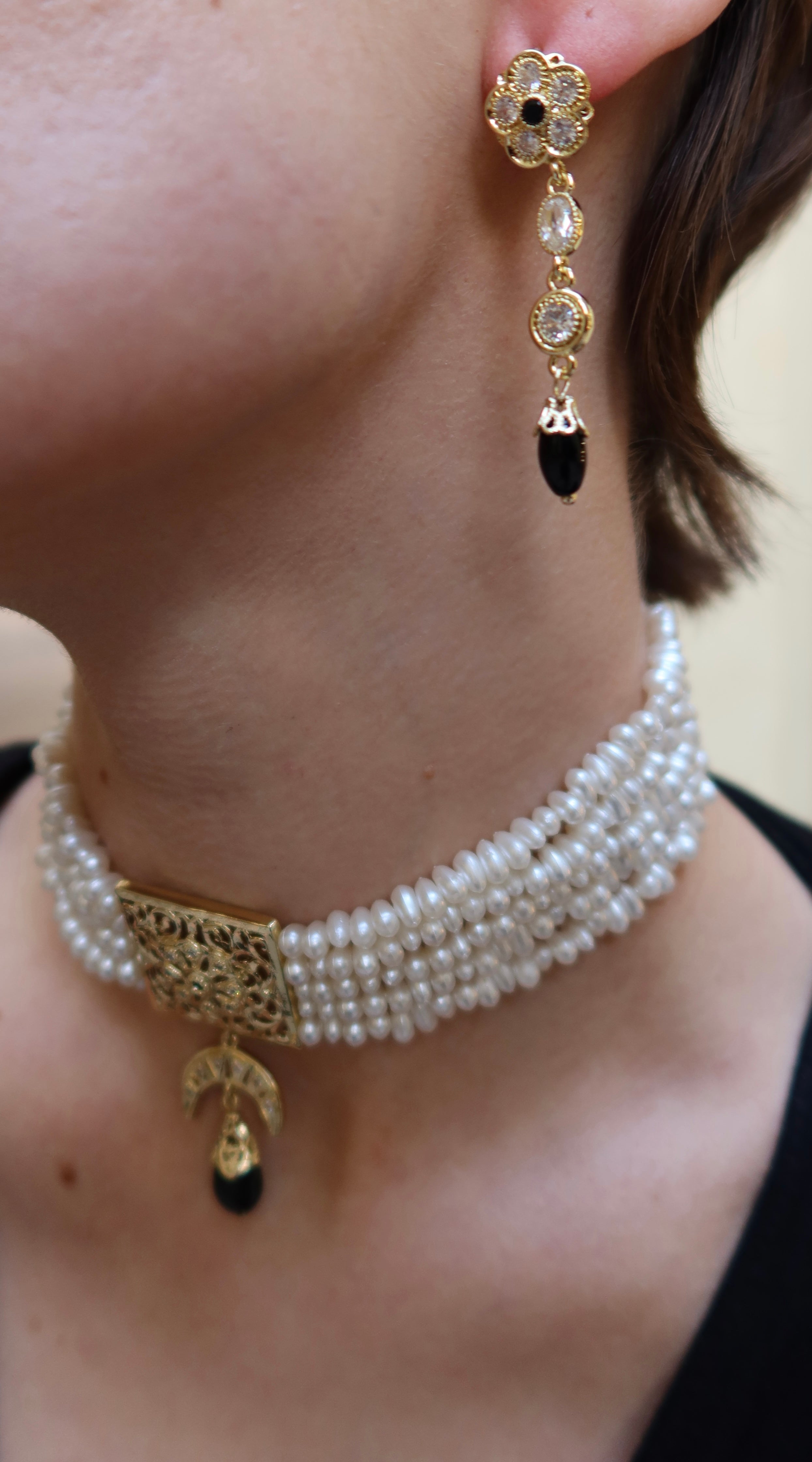 Detail of black and gold flower-shaped earrings with a chic finish