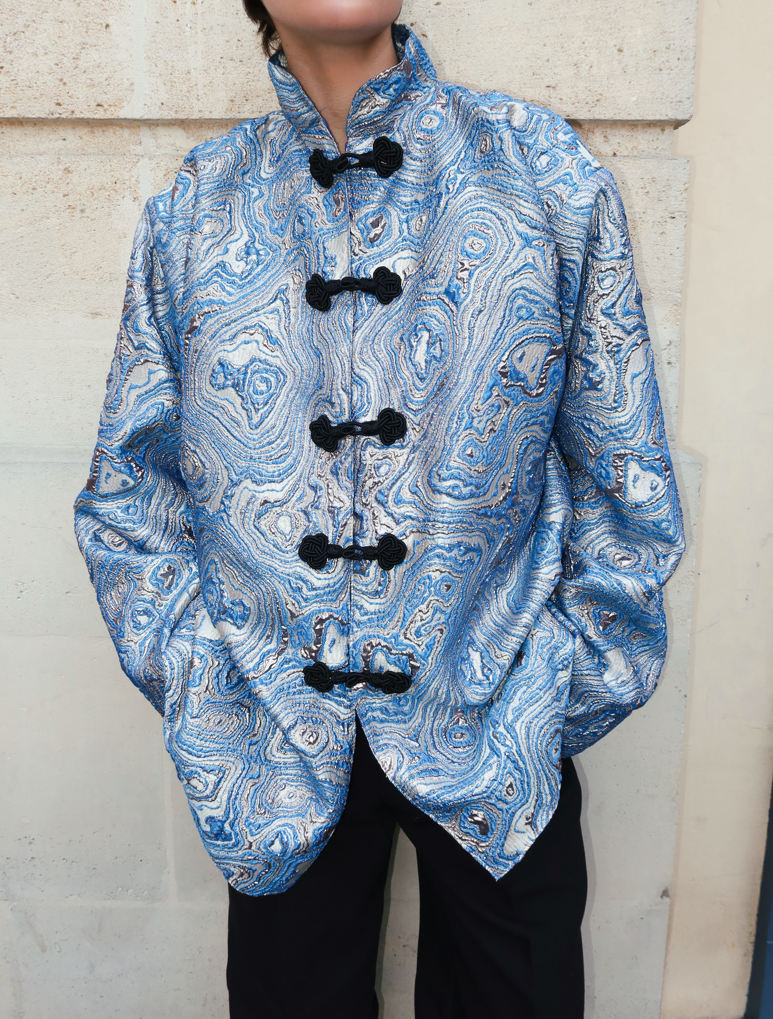Close-up of handmade black Moroccan hooks on a blue brocade jacket