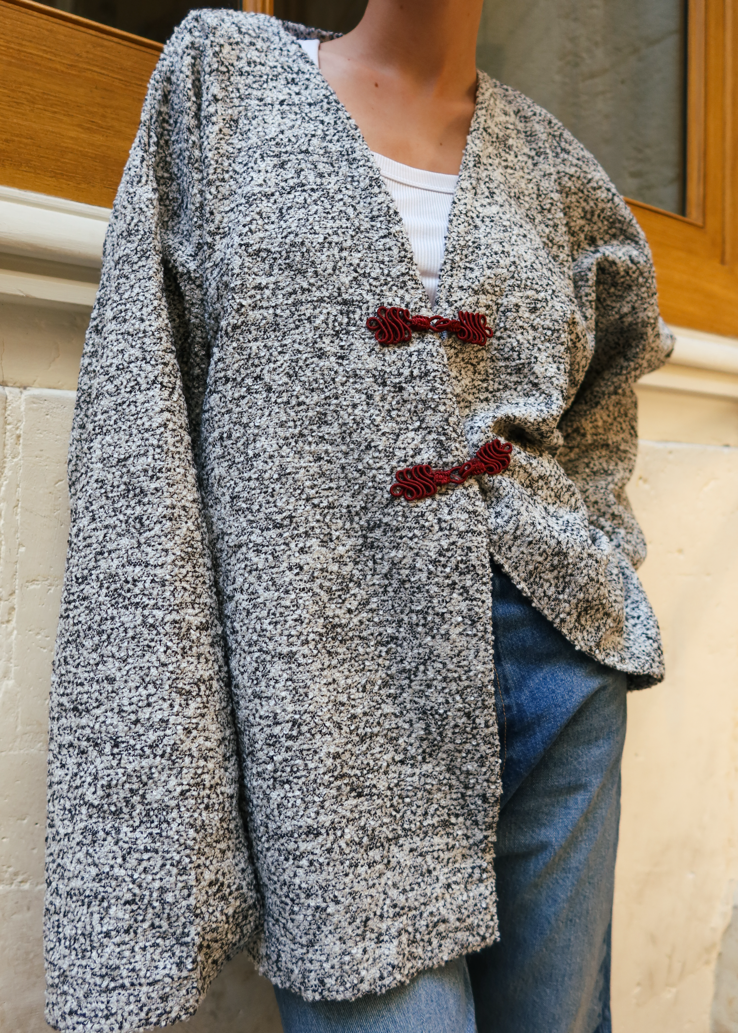 Gray and black bouclé wool jacket with movement revealing a refined bouclé texture and burgundy hooks