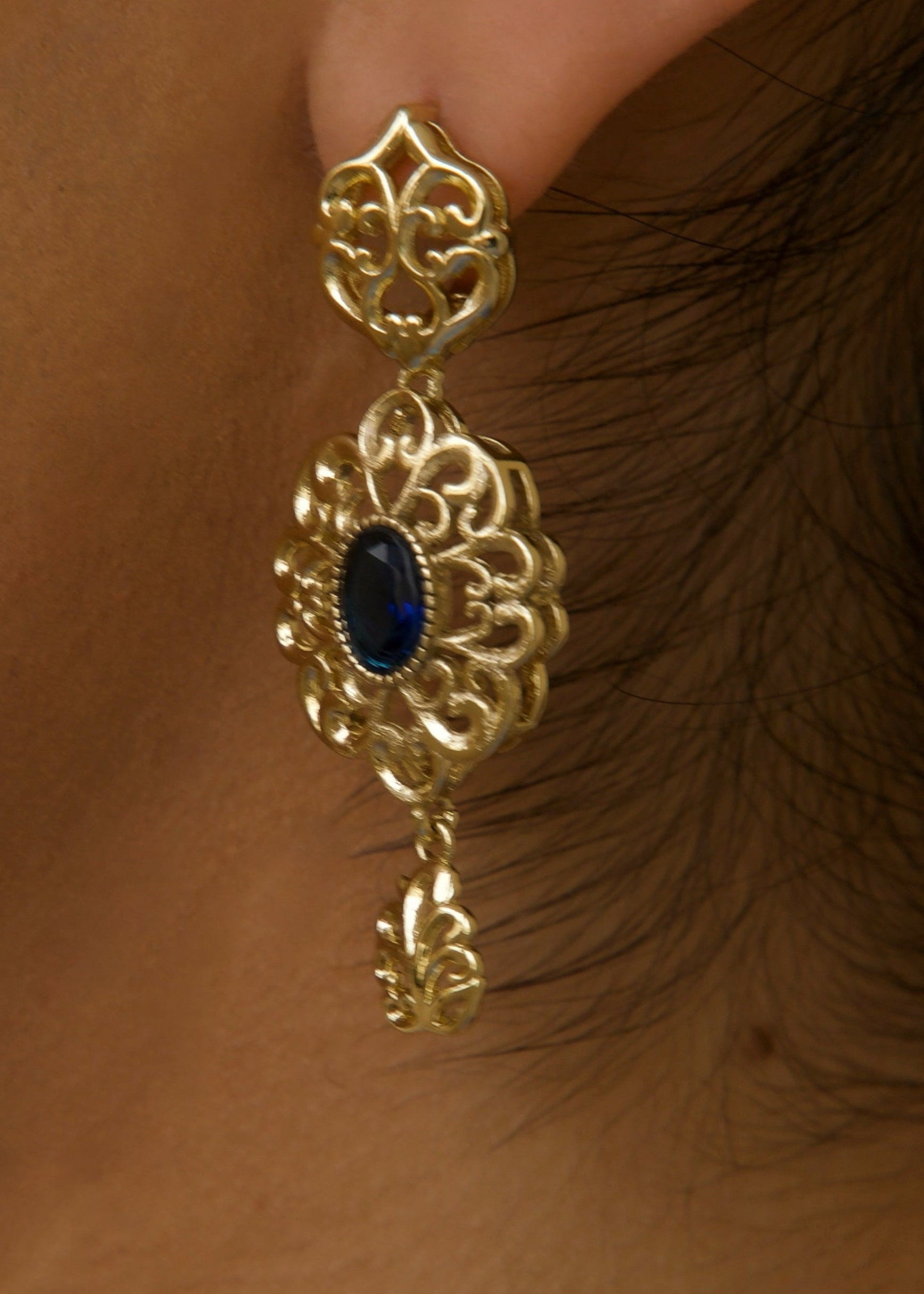 Detail of round gold and blue earrings with a shiny finish and elegant contrast
