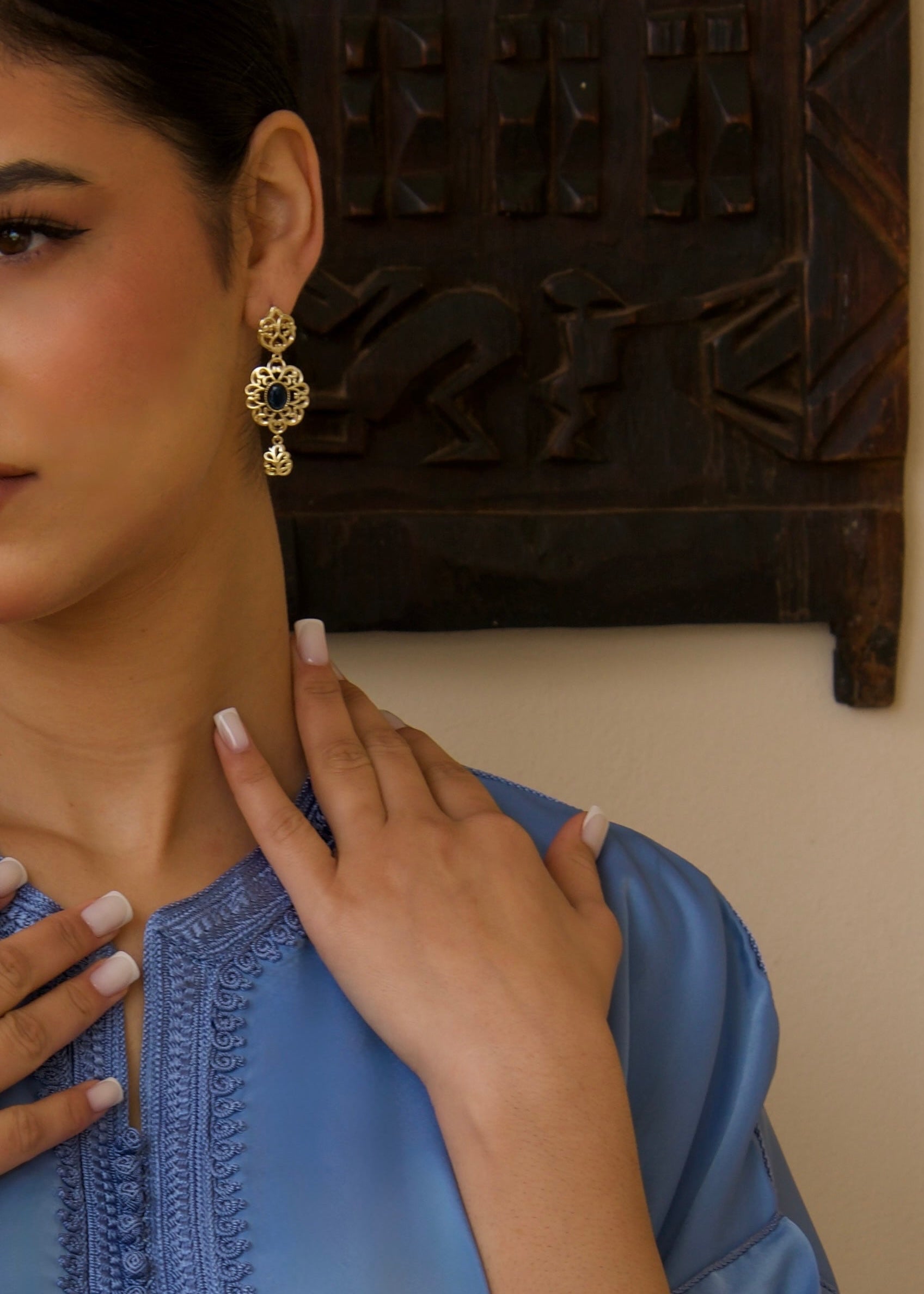 Round gold and blue earrings worn