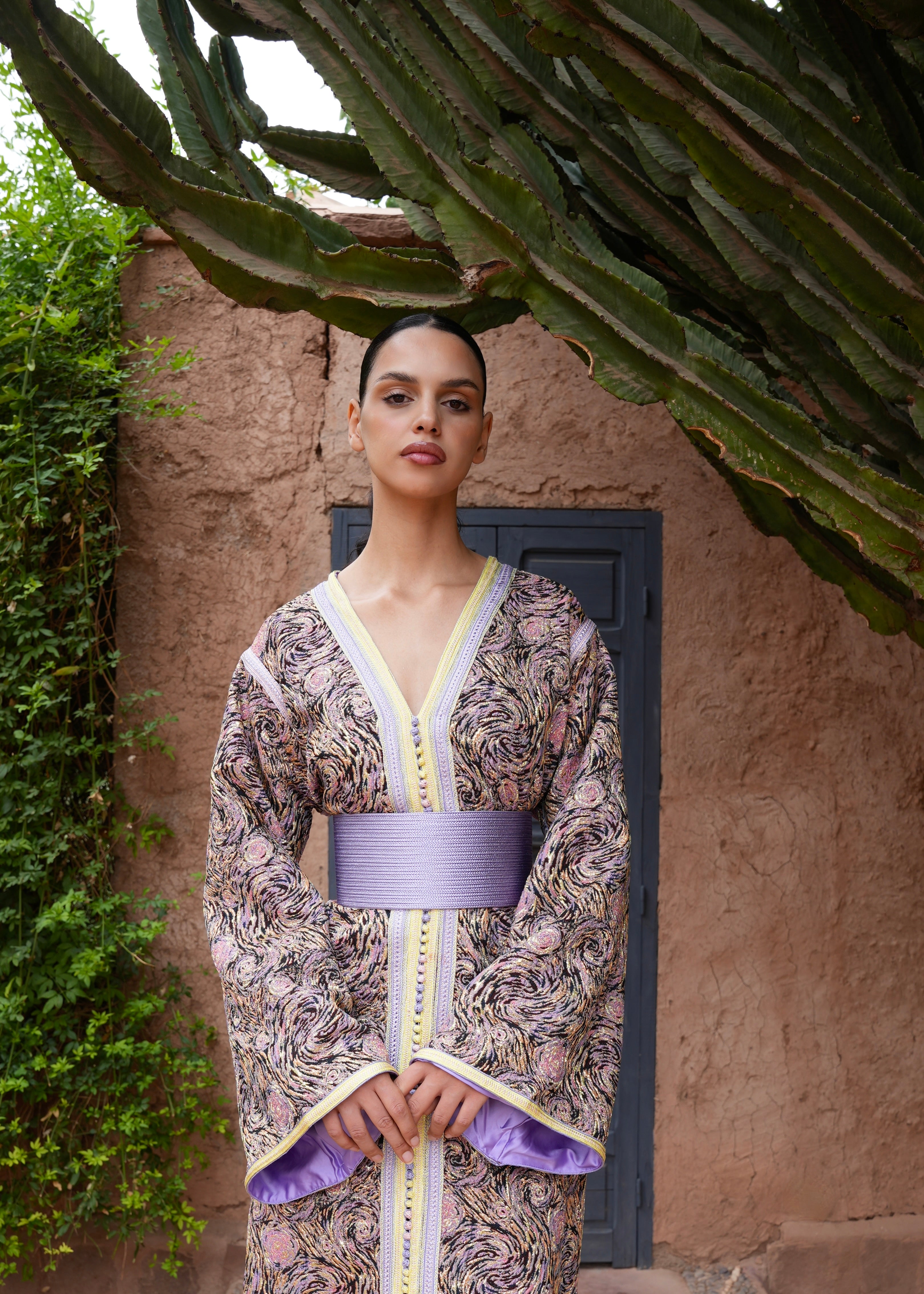 Woman wearing a multicolored brocade Kaftan with purple and yellow details, front view