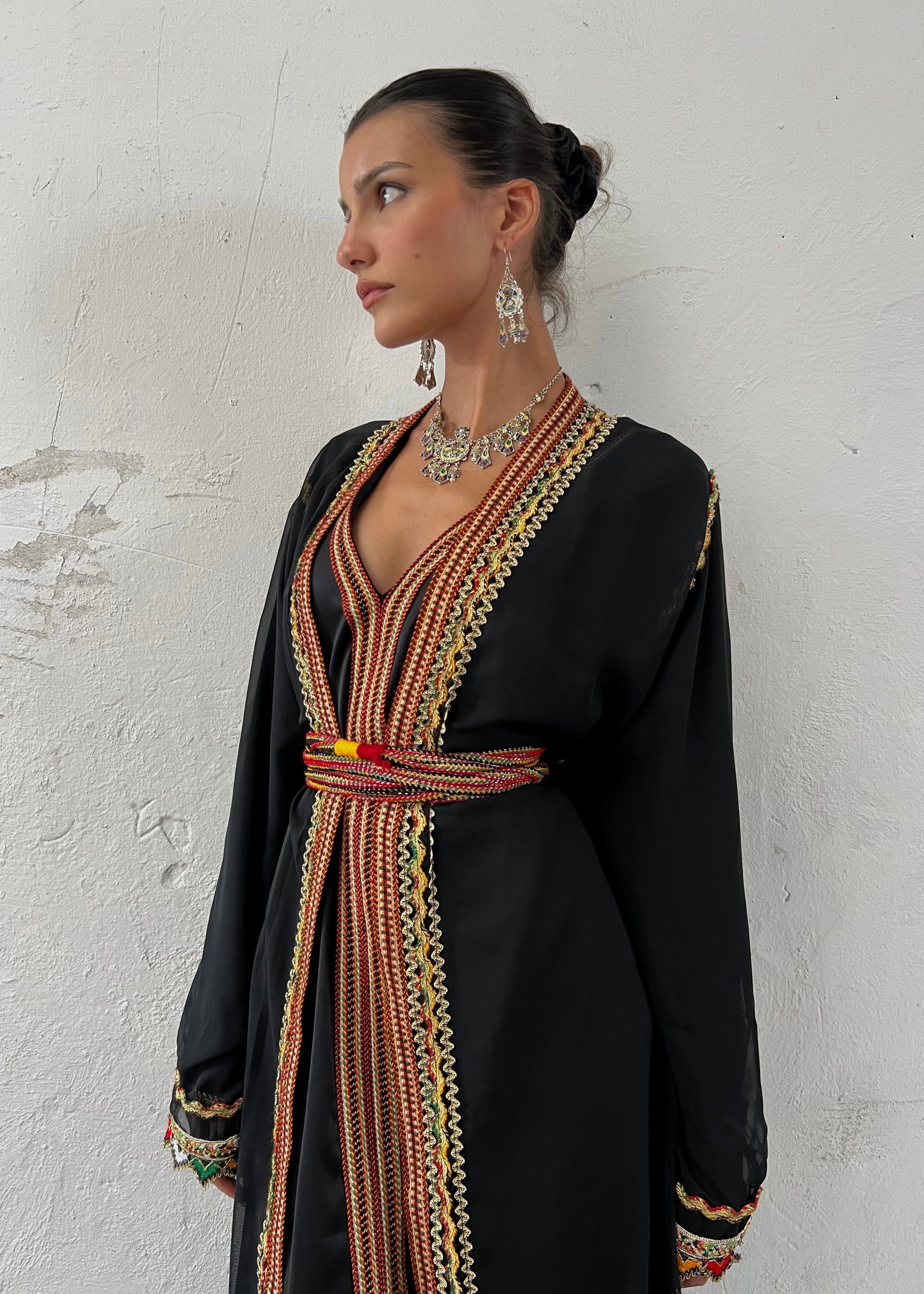 Detail of the black Kabyle Kaftan , showing up close the traditional Berber embroidery, the precision of the motifs and the brilliance of the colors on a black background.