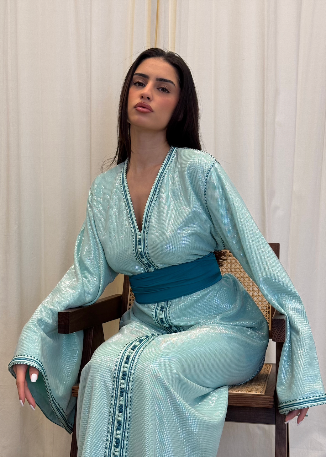 Kaftan in turquoise-blue sequined silk lamé captured in motion, highlighting the lightness of the fabric and the brilliance of the sequins.