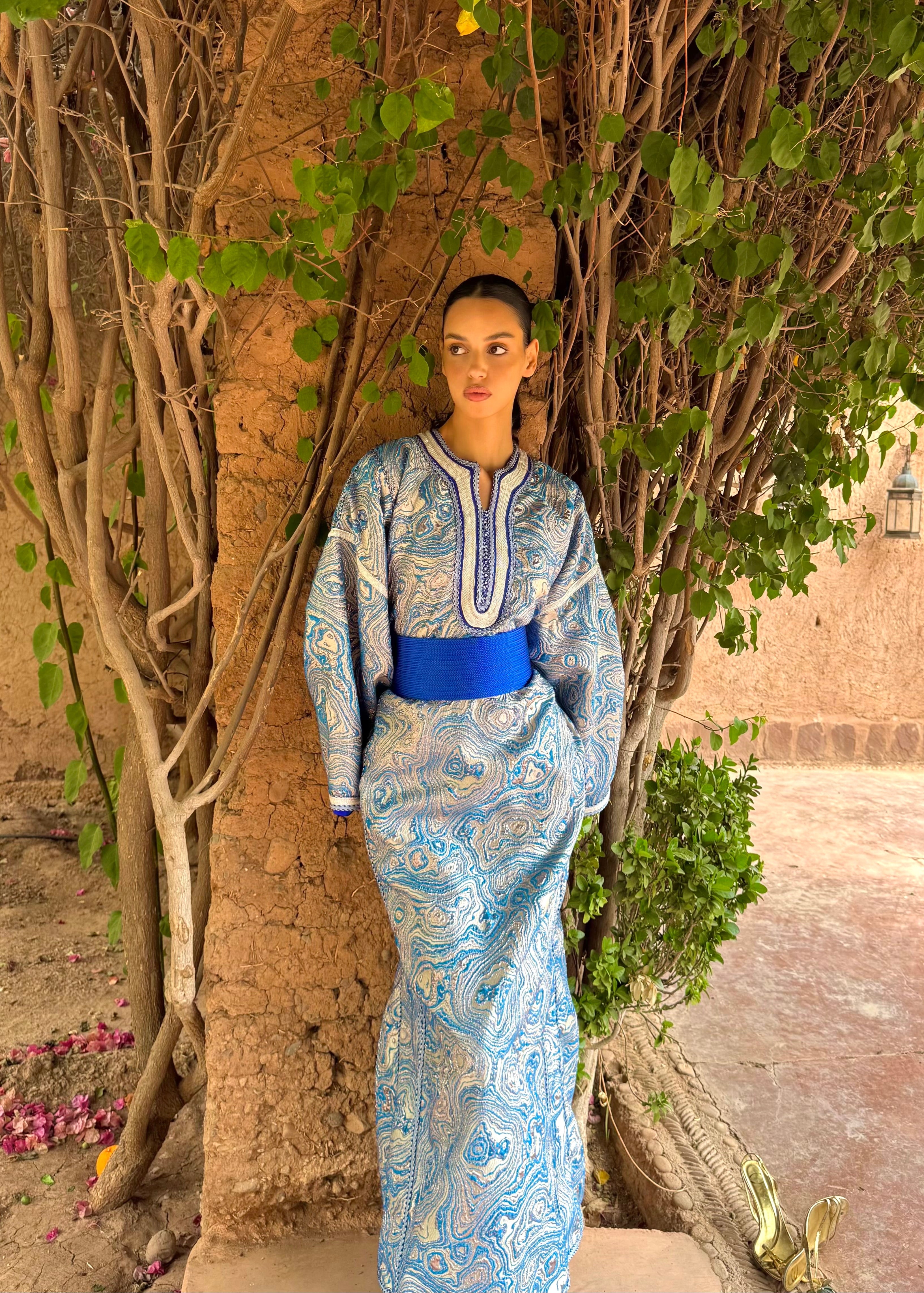 Front view of a model wearing a modern Kaftan in blue brocade, elegance and details visible