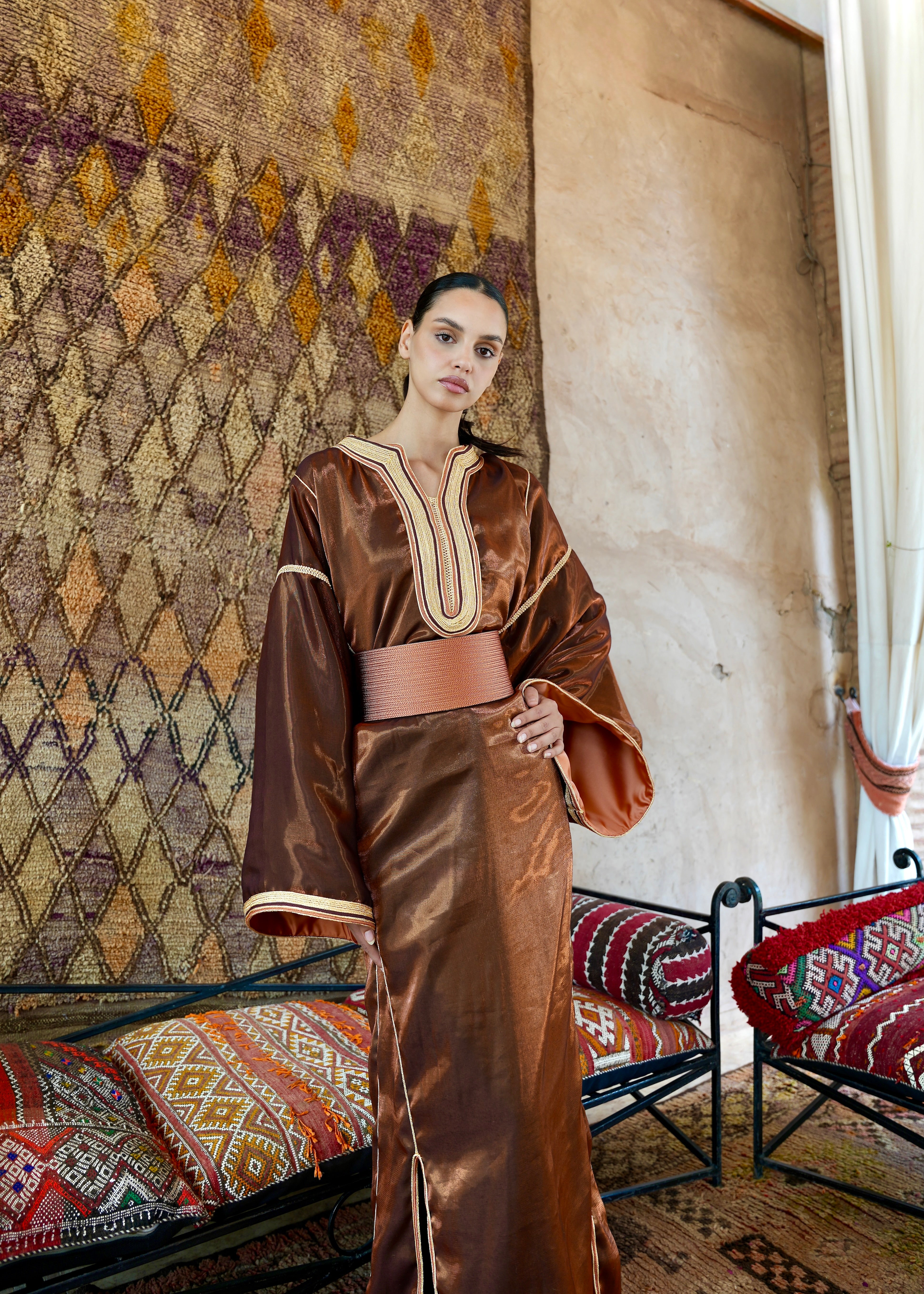 Full-length view of a model wearing a modern Kaftan in metallic bronze satin, elegant cut
