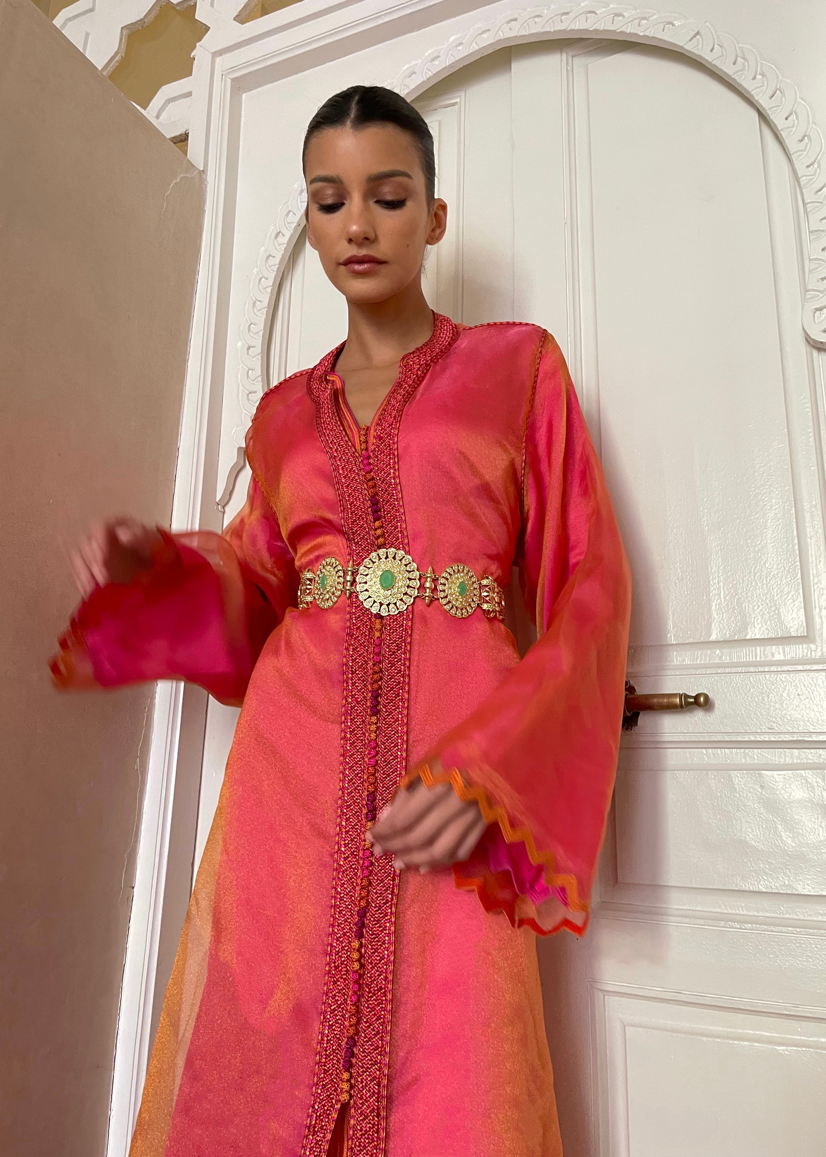 Kaftan in orange-pink organza changeante with zigzag detailing seen from the front, highlighting the iridescent sheen of the fabric and the fluid cut.