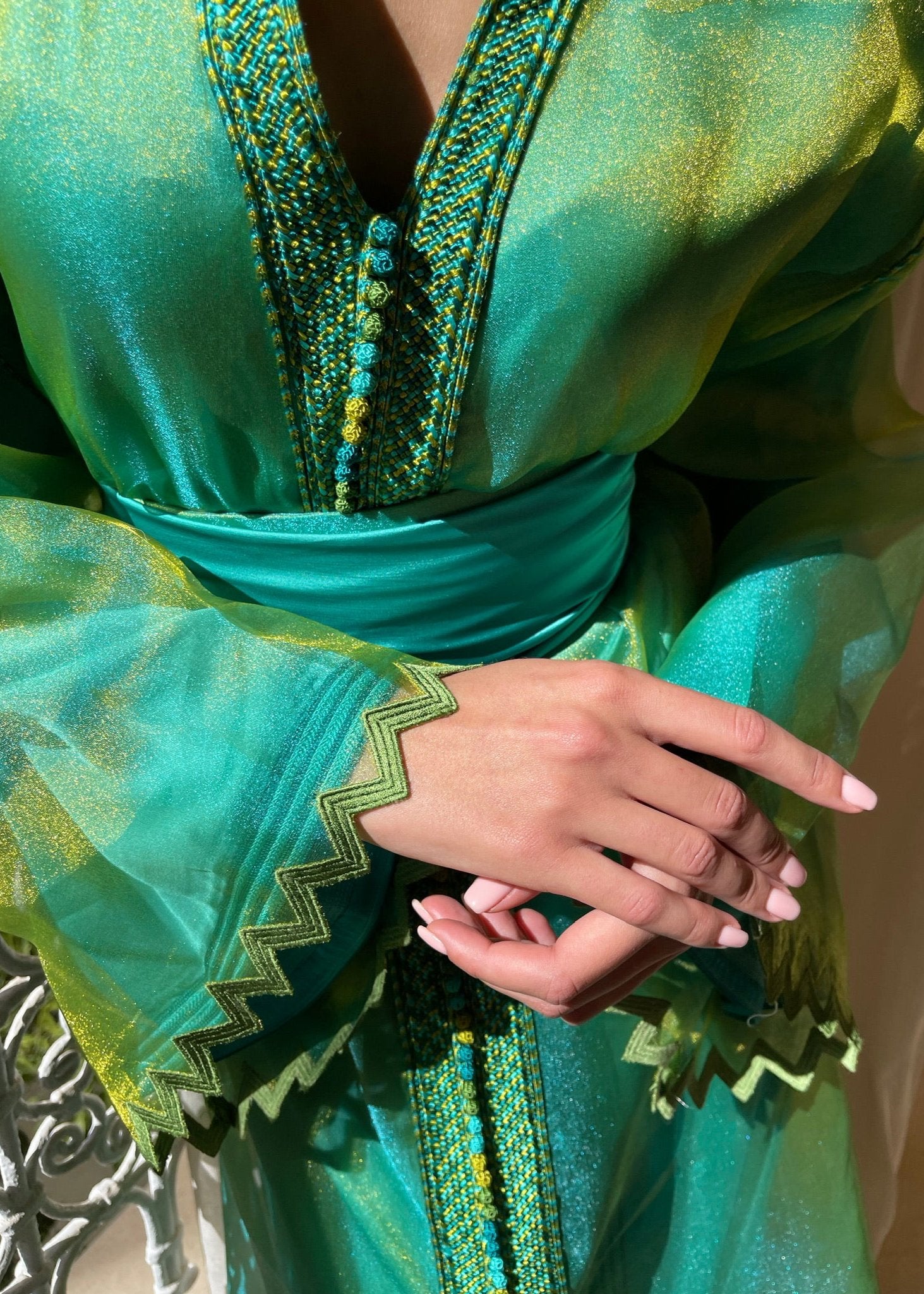 Detail of the Kaftan in green and blue organza, showing up close the delicate texture of the fabric, the careful finishing and the subtle reflections of the colors.