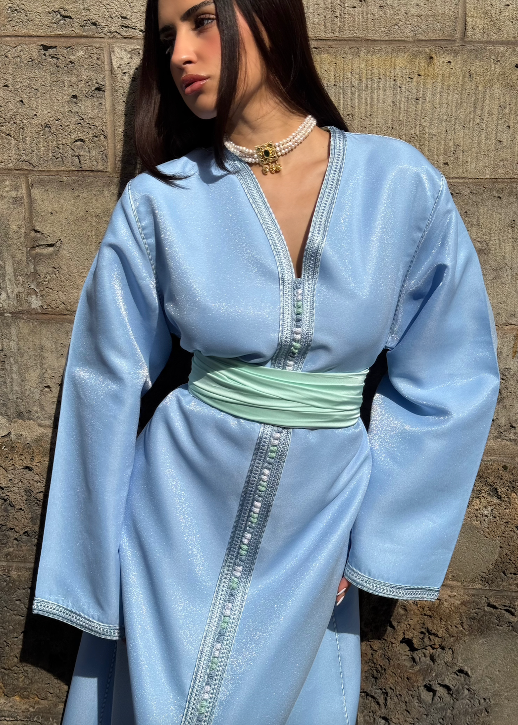 Blue satin Kaftan captured in motion, highlighting the fluidity of the fabric and the softness of the blue reflections.