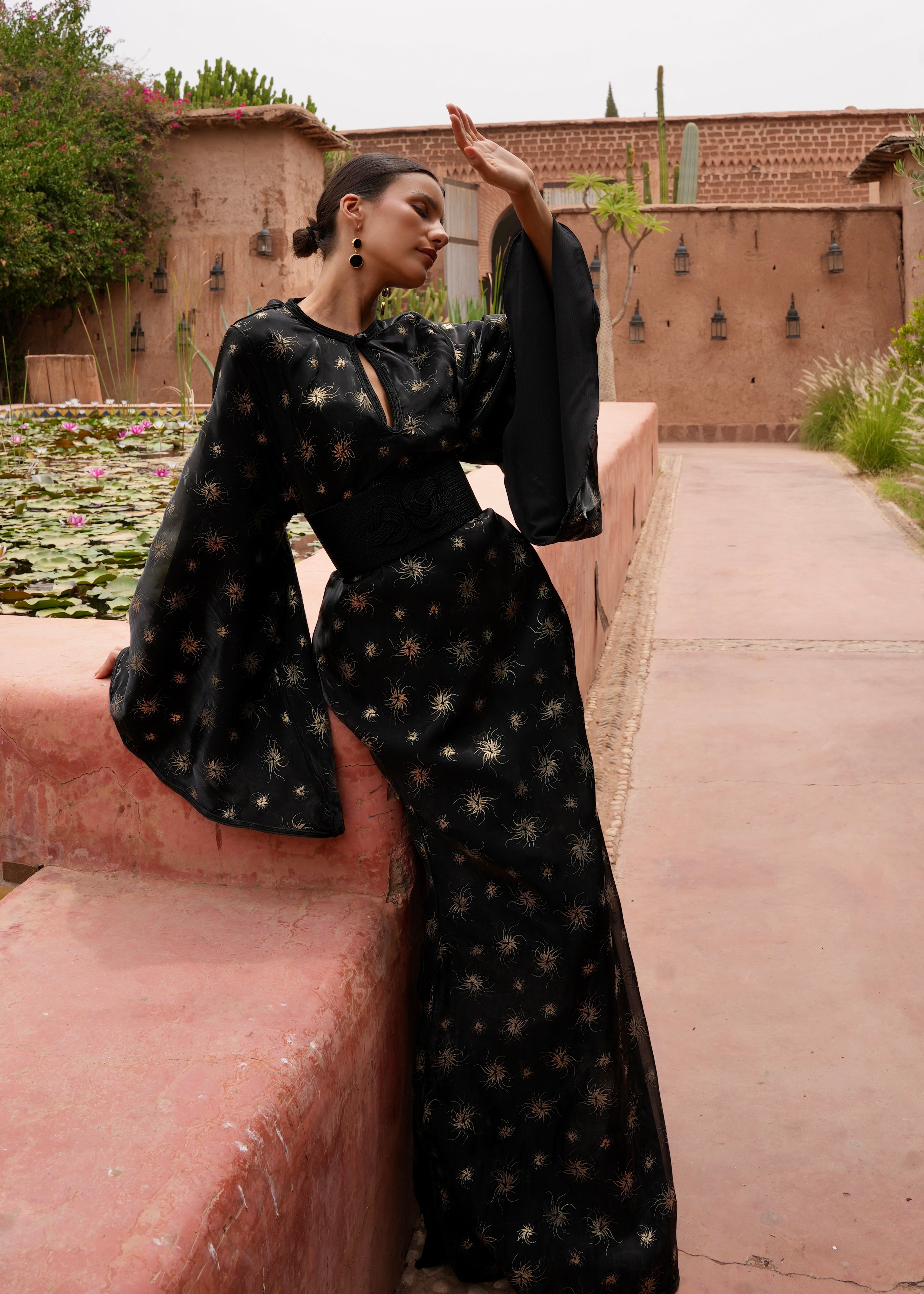 Full-length view of a model wearing the black organza evening Kaftan with gold print