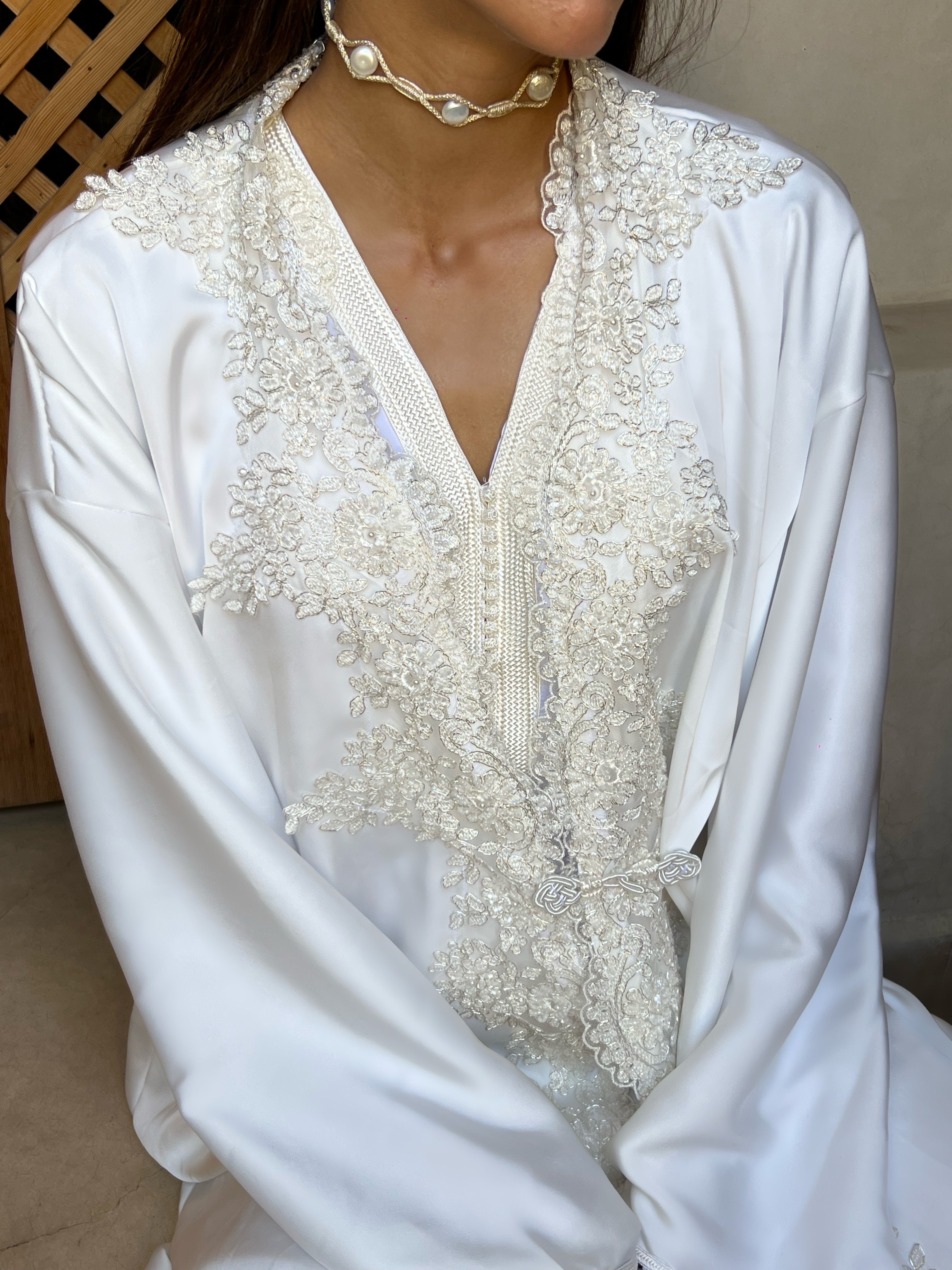 Detail of the bridal Kaftan in white silk drape, glittering sequined lace and haute couture finishes