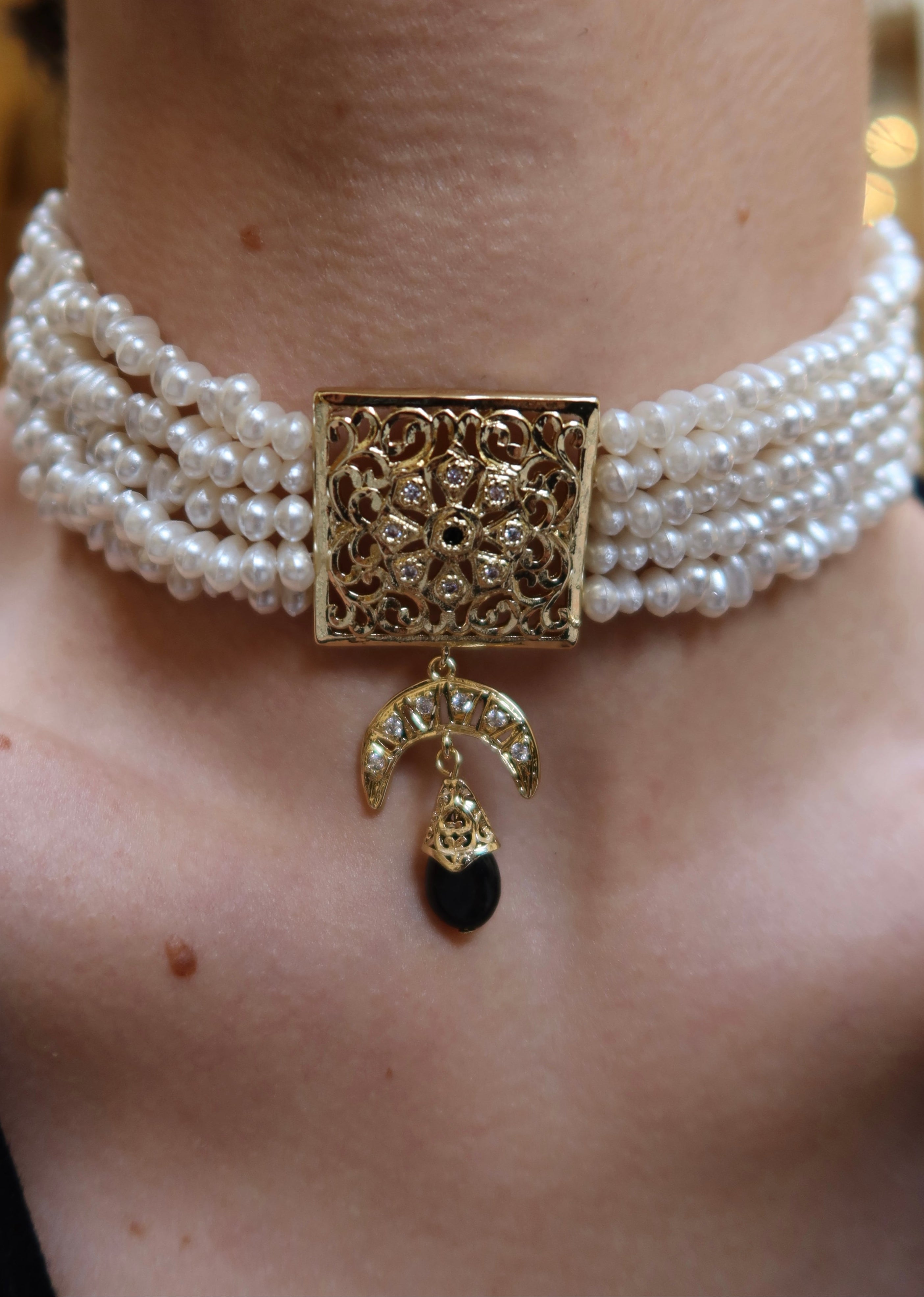 Detail of gold and black beaded necklace with black pendant