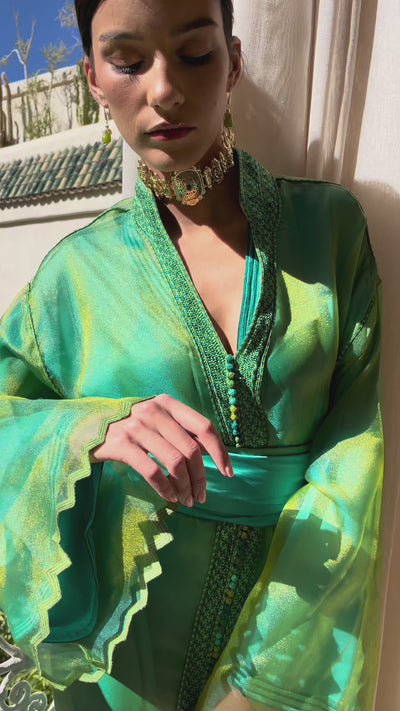 Video of a green and blue organza Kaftan , worn by a model, highlighting the iridescent sheen of the fabric and the elegance of the flowing cut.