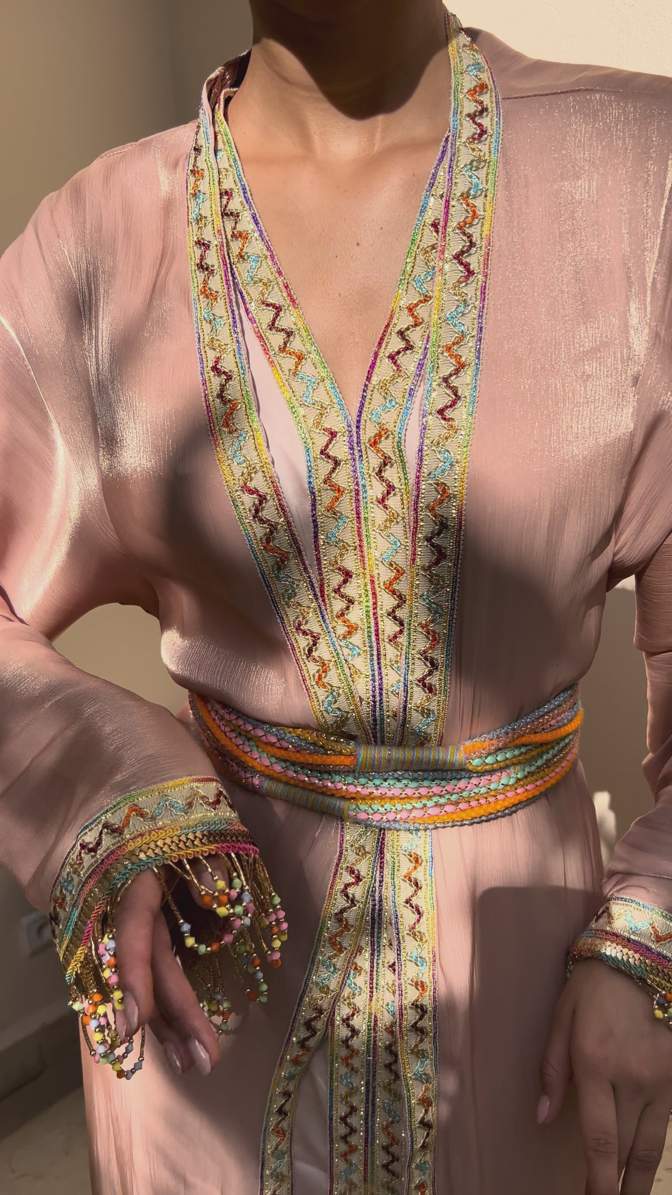 Video of a Kabyle Kaftan in embroidered pink organza, with traditional wool belt and beaded sleeves - refined Berber attire for weddings or ceremonies.