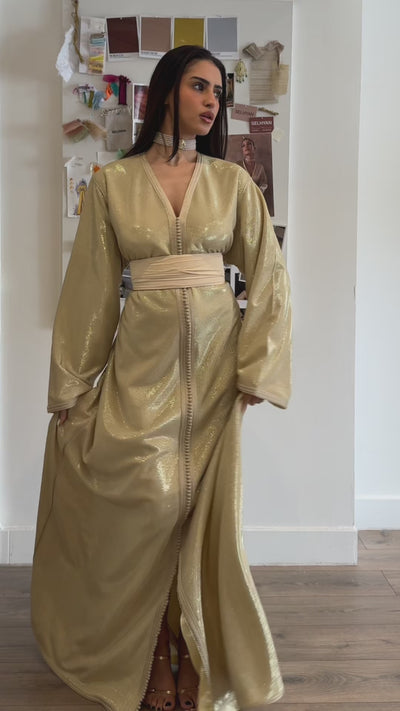 Video of a Kaftan in beige silk lamé, with a shiny, elegant fabric. A traditional Oriental dress perfect for ceremonies, weddings and sophisticated evenings.