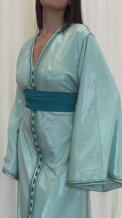 Video of a Kaftan in turquoise-blue sequined silk lamé, elegant cut with shimmering highlights. A luxurious oriental dress worn on the move, ideal for evenings out or weddings.
