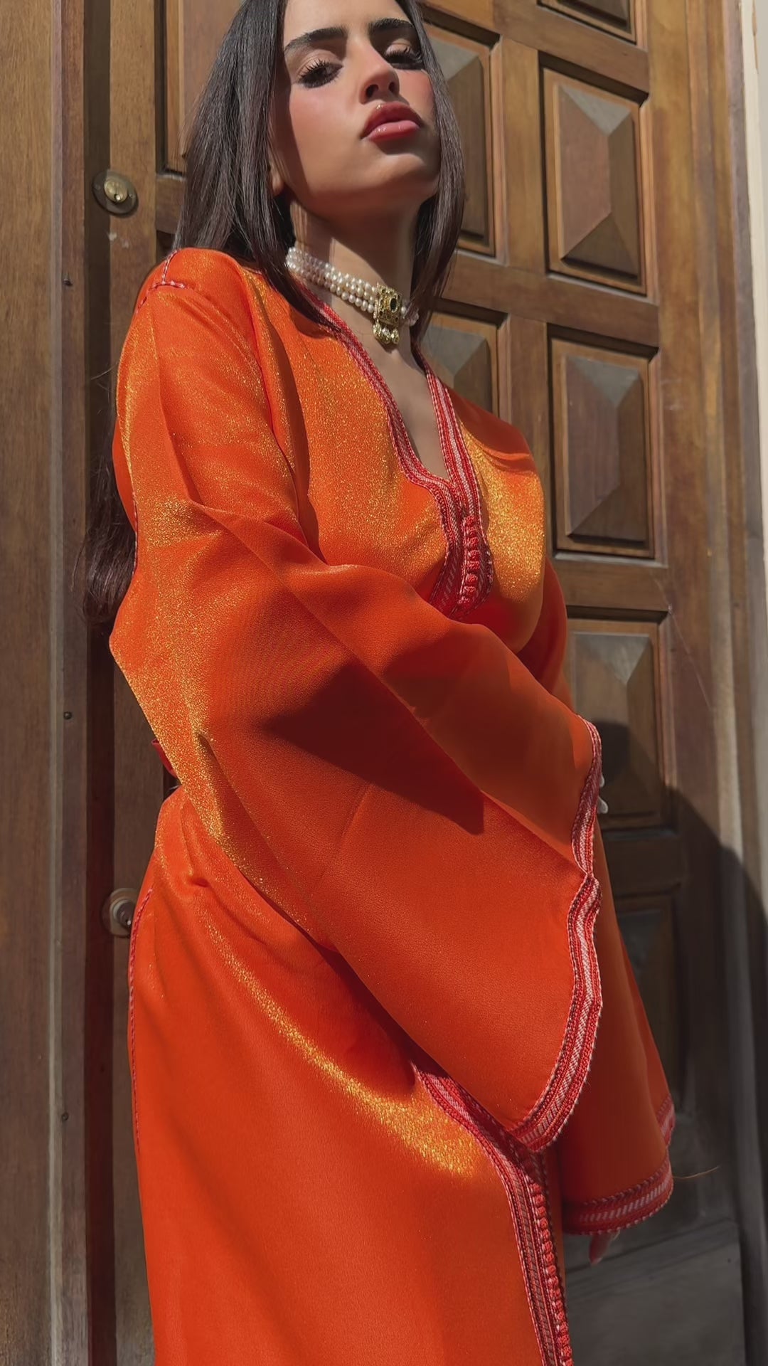 Video of a Kaftan in luminous orange satin, elegant cut with meticulous finishing. A traditional Moroccan dress perfect for festive events, parties or ceremonies.