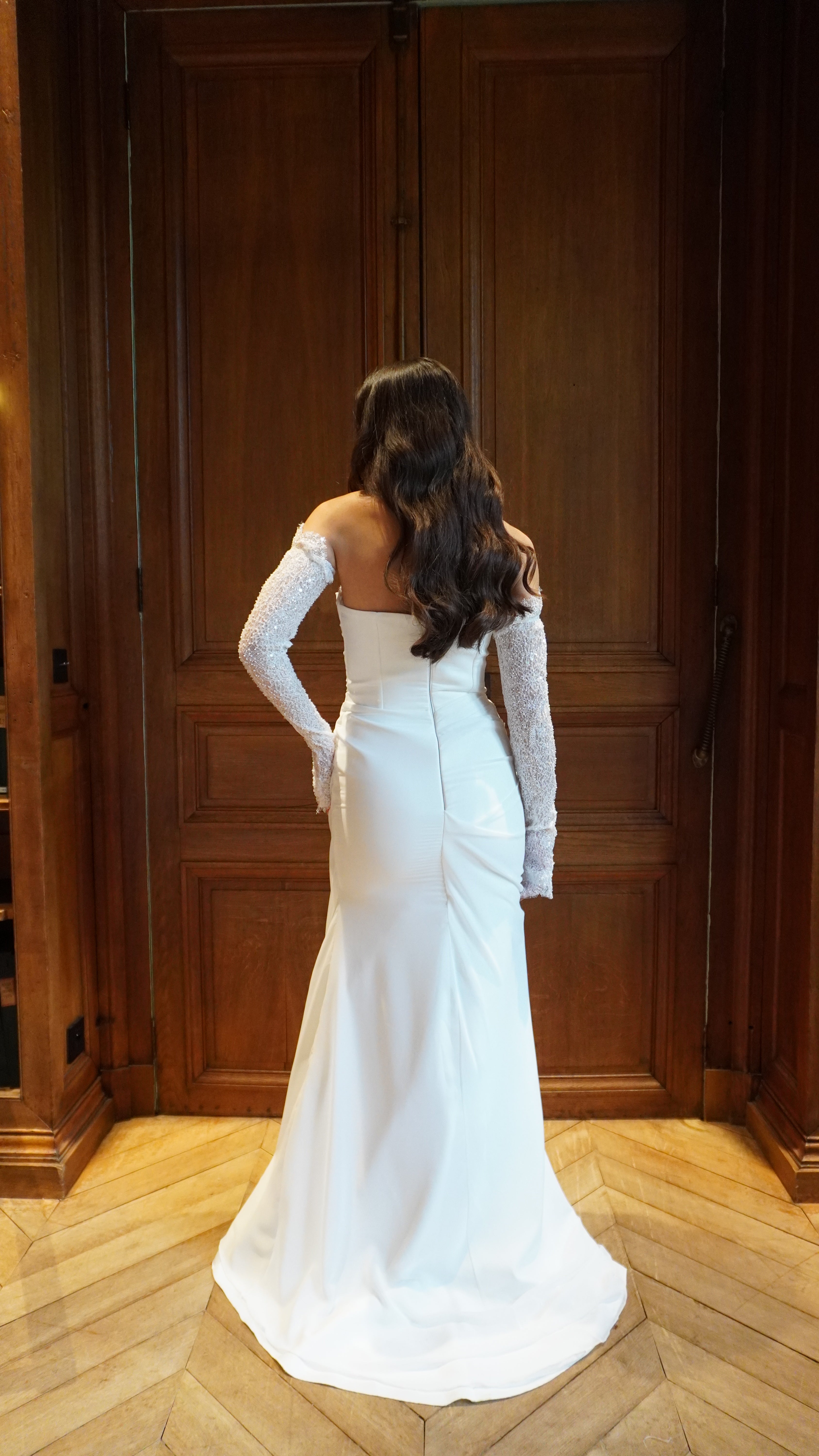 Strapless draped mermaid wedding gown with lace detail seen from the back, revealing refined lines and a fitted cut.