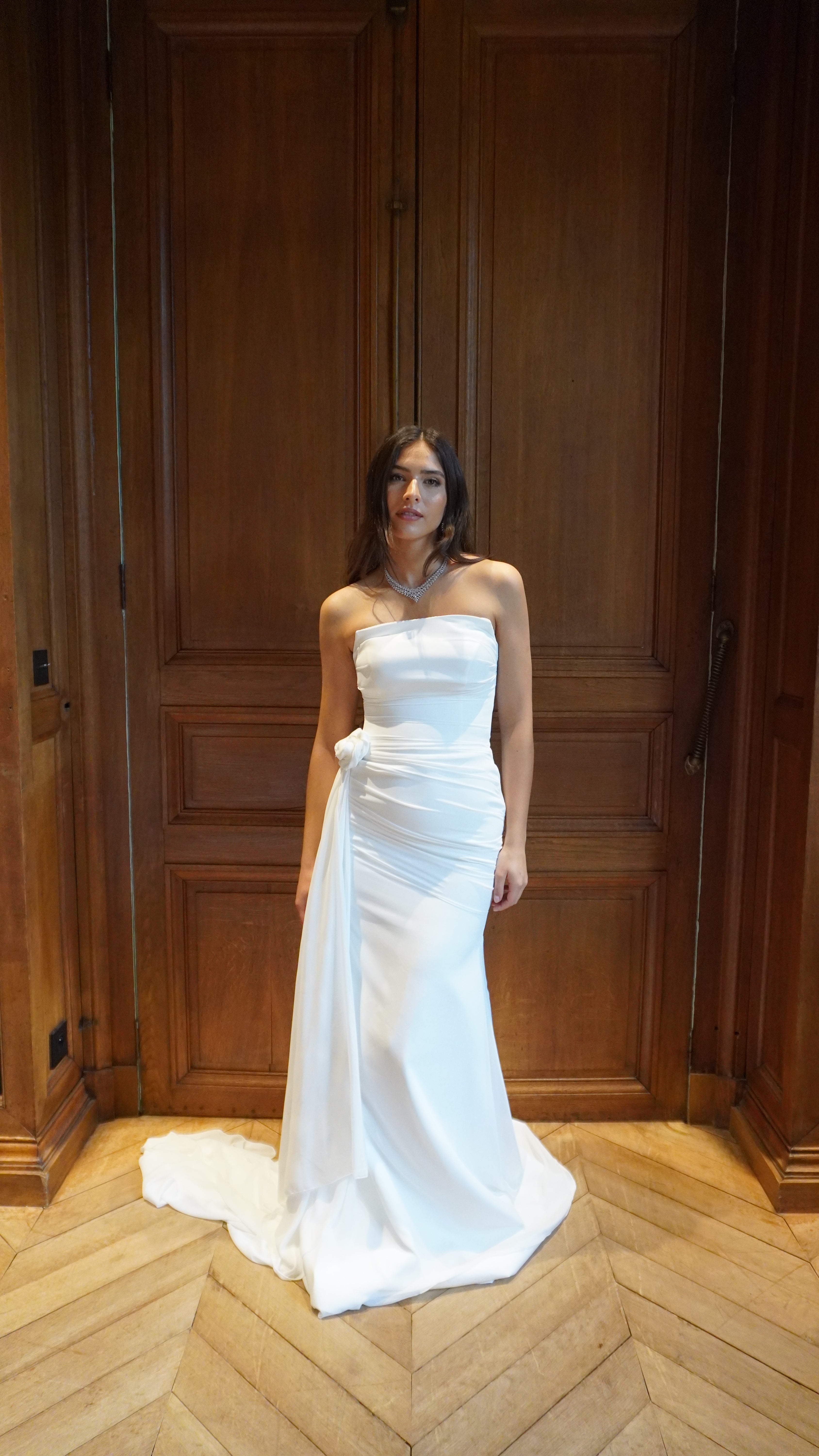 Draped mermaid wedding gown with removable front flower, showcasing an elegant, fitted silhouette.