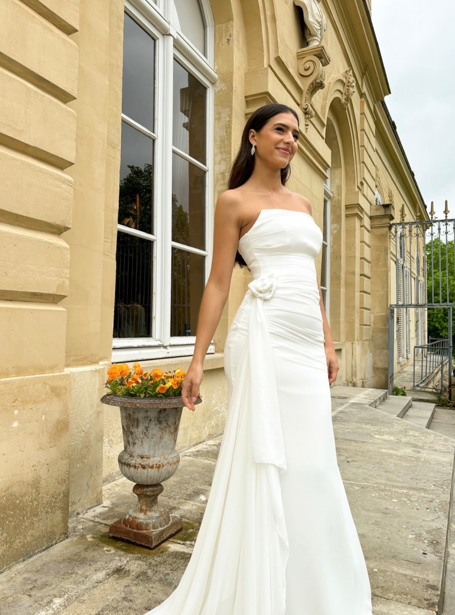Draped mermaid wedding gown with removable front flower, showcasing an elegant, fitted silhouette.