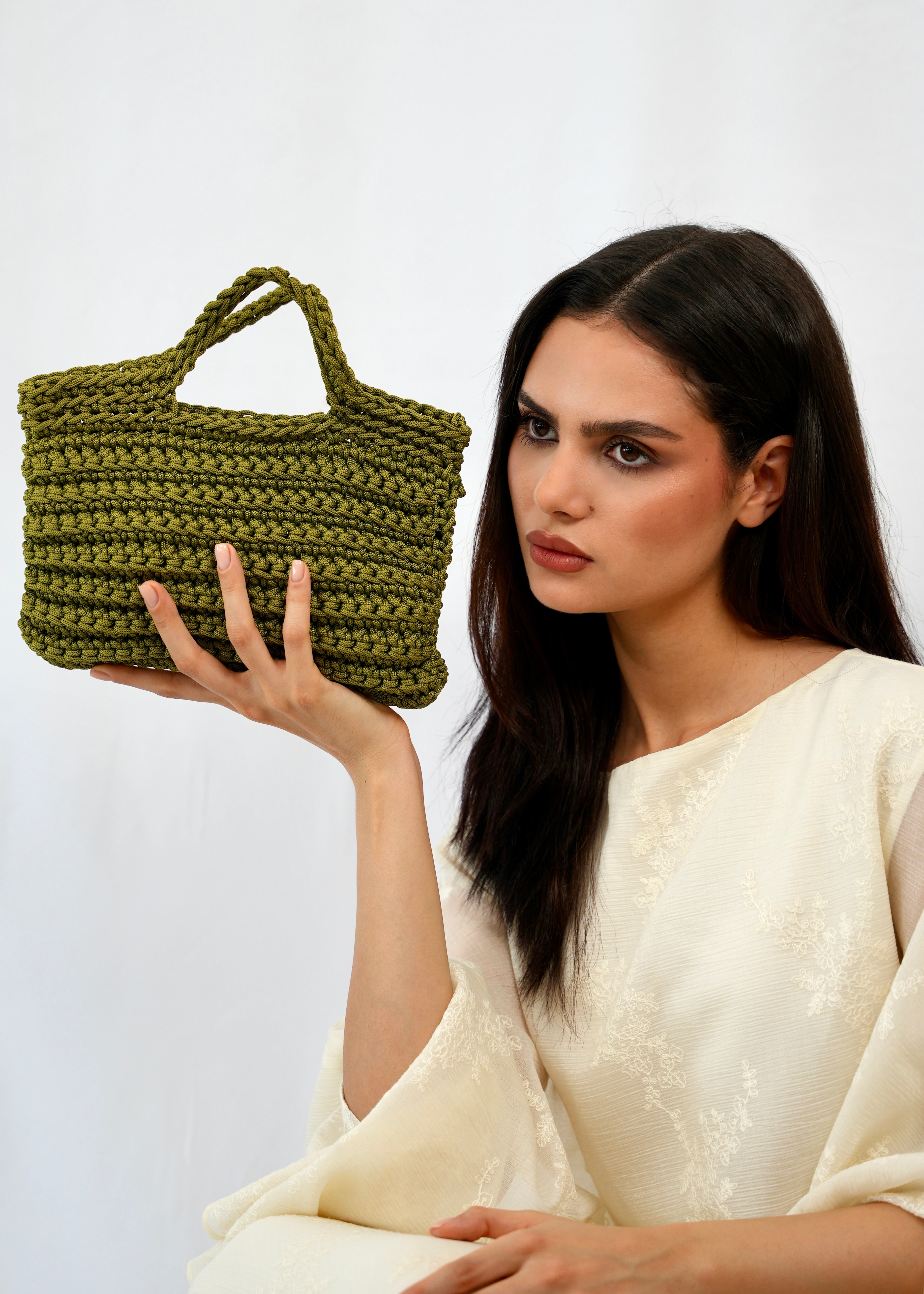 Handmade khaki green crochet square bag in Marrakech, worn by a model in the studio