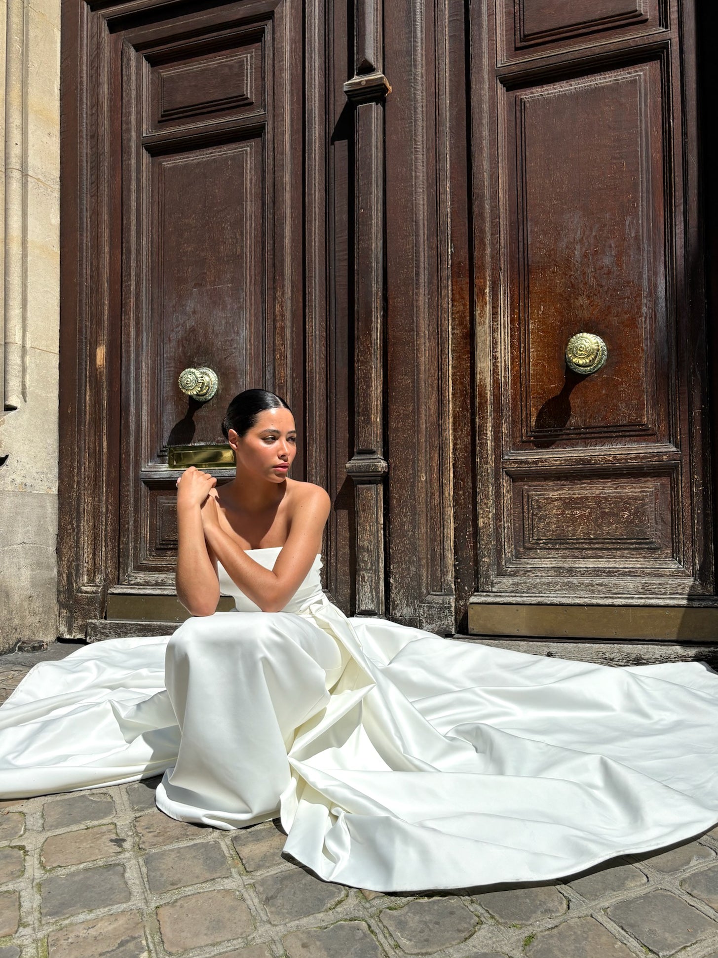 Princess wedding overskirt in Palace satin – bride seated, highlighting the drape of the fabric
